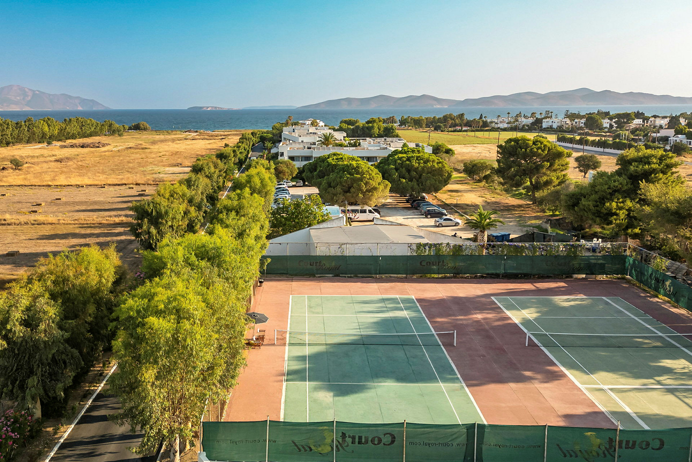 Tennisbaner med landskab og hav i baggrunden. (AI-genereret tekst)