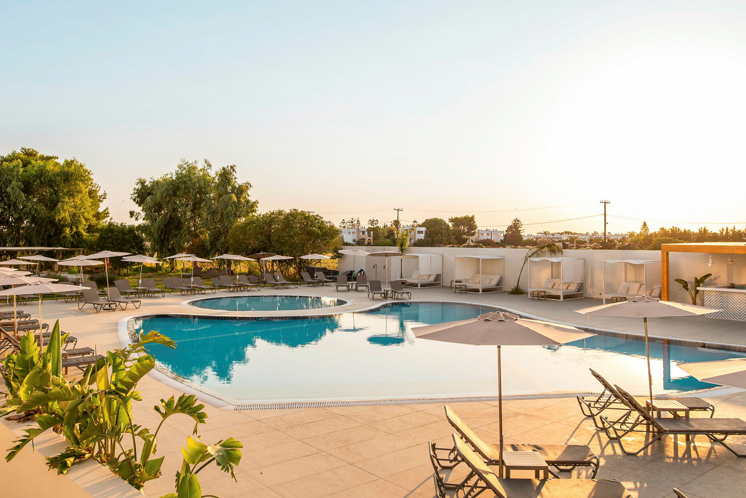 Billede af en udendørs pool med liggestole og parasoller på et hotelområde. (AI-genereret tekst)