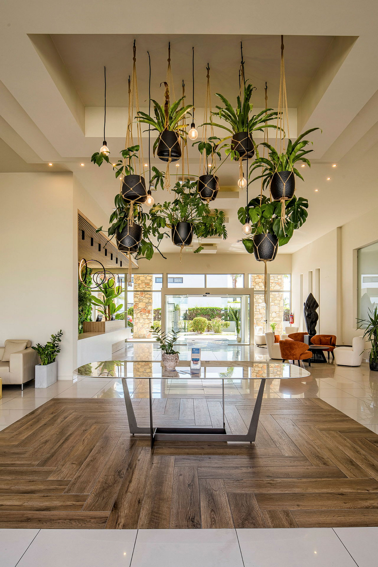 En moderne hotellobby med hængende planter og glasbord. (AI-genereret tekst)