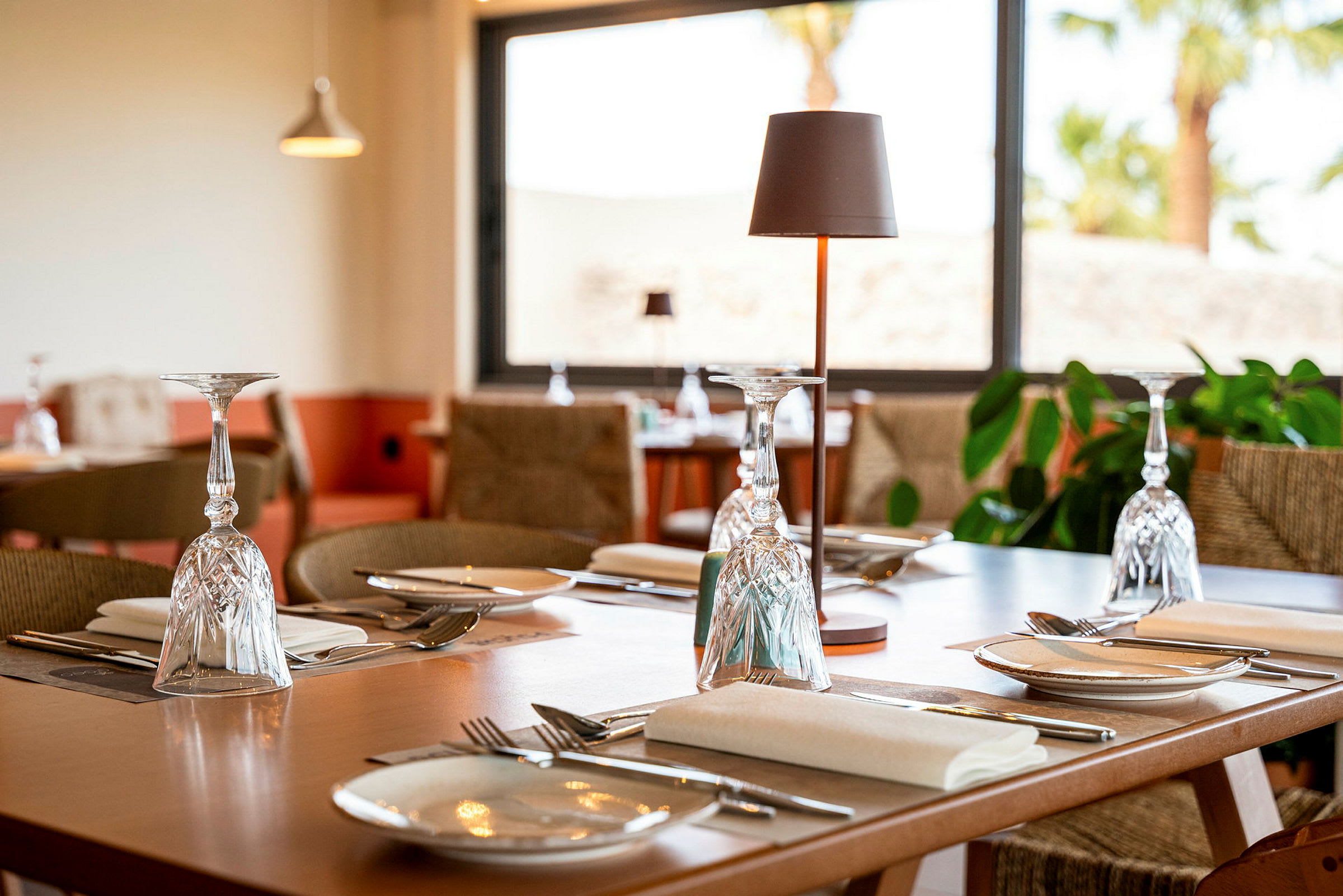 Et dækket bord med glas, bestik og tallerkener i en restaurant. (AI-genereret tekst)