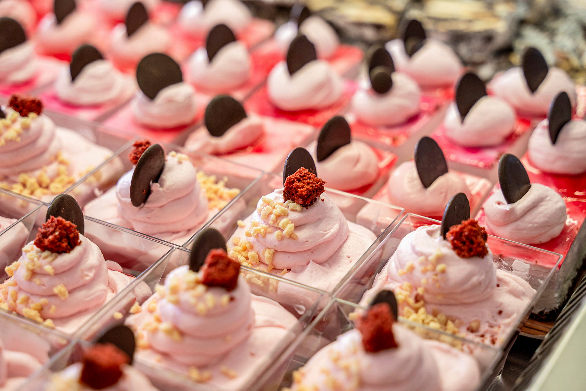 Rosa desserter pyntet med chokoladebidder og krymmel. (AI-genereret tekst)