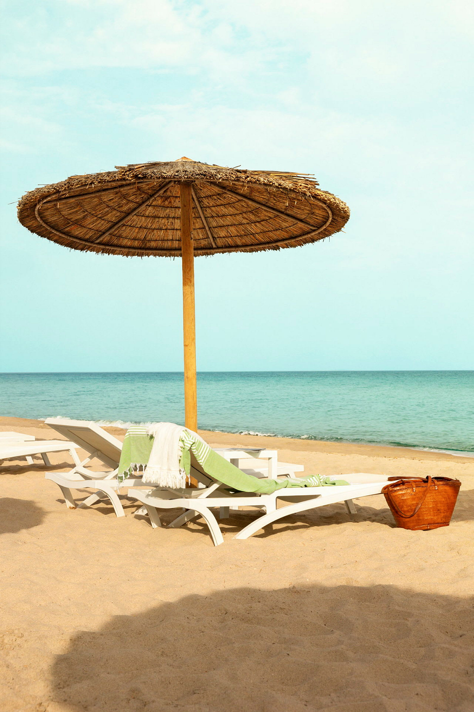 Strand med parasol, liggestole og en kurv. (AI-genereret tekst)