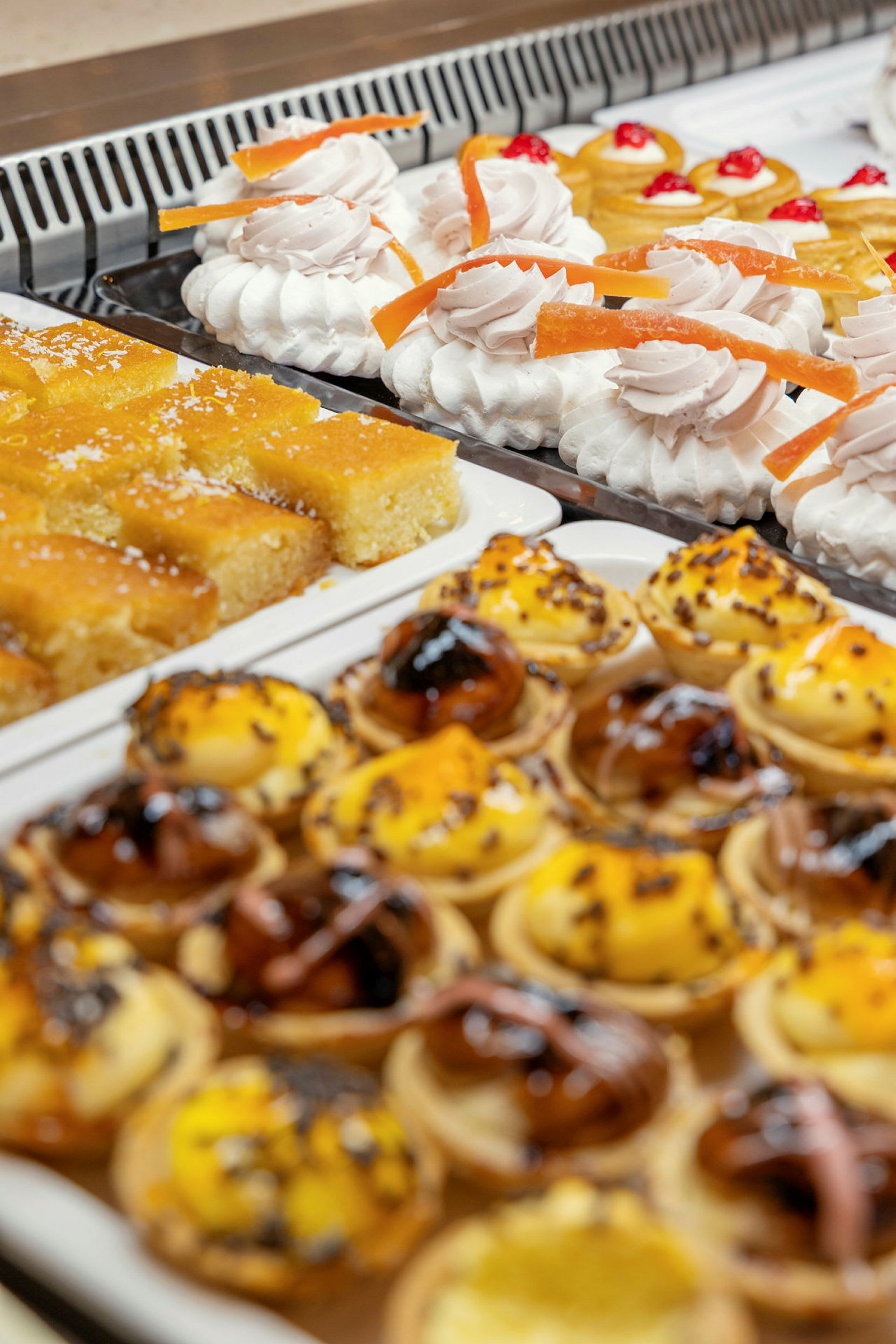 En buffet med bagværk, herunder små kager med flødeskum, kagestykker og små tærter. (AI-genereret tekst)