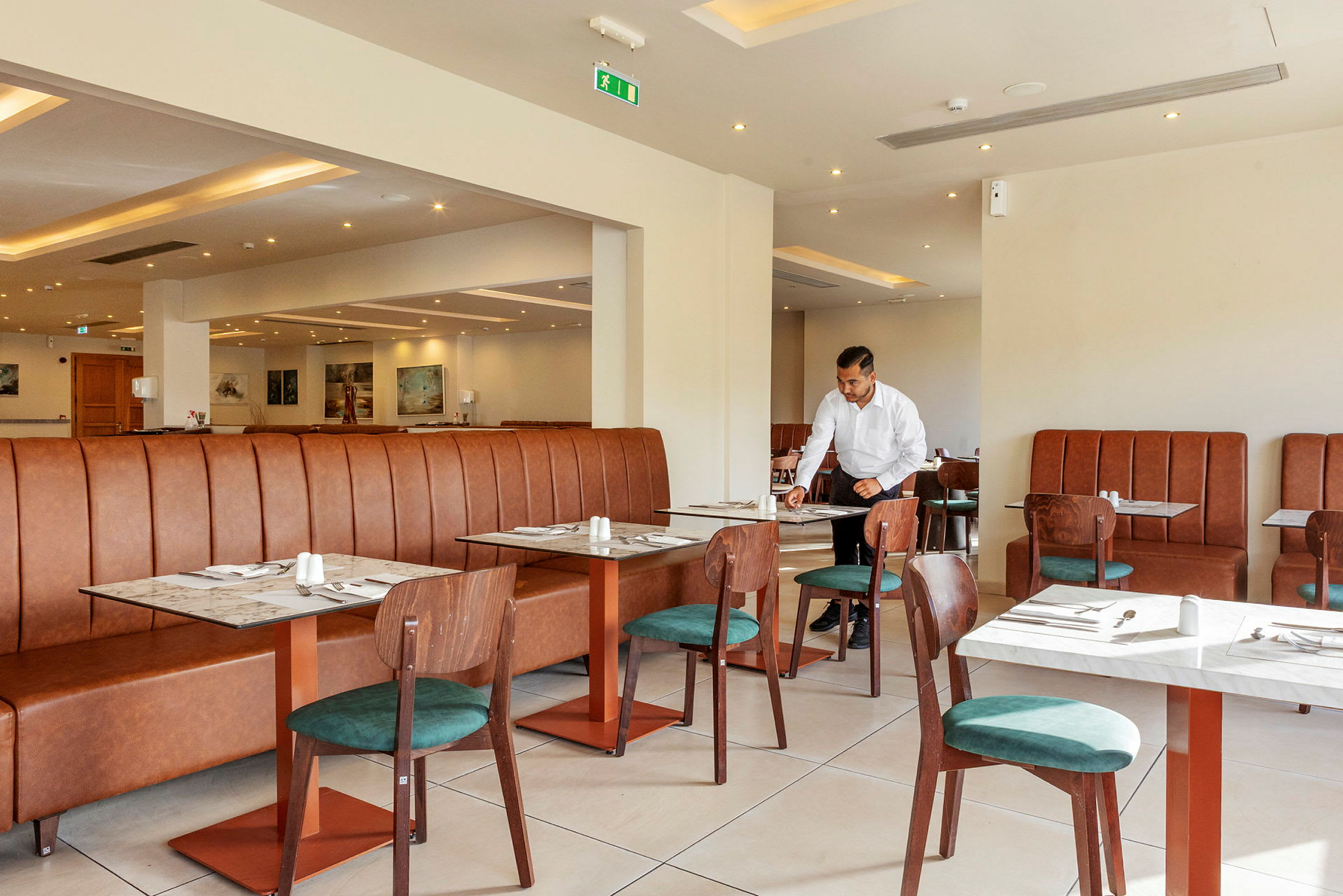 Interiør af en restaurant med borde og stole samt en brun lædersofa. (AI-genereret tekst)