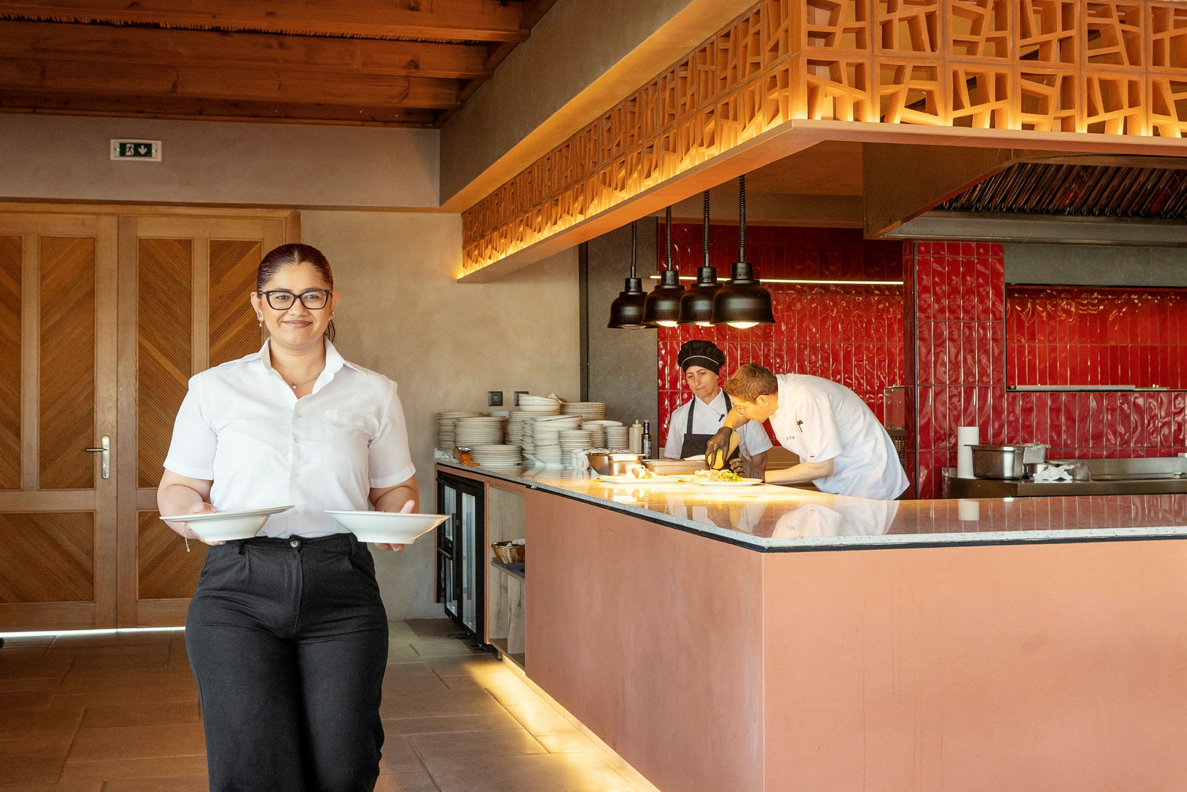En restaurantinteriør med personale og køkken. (AI-genereret tekst)