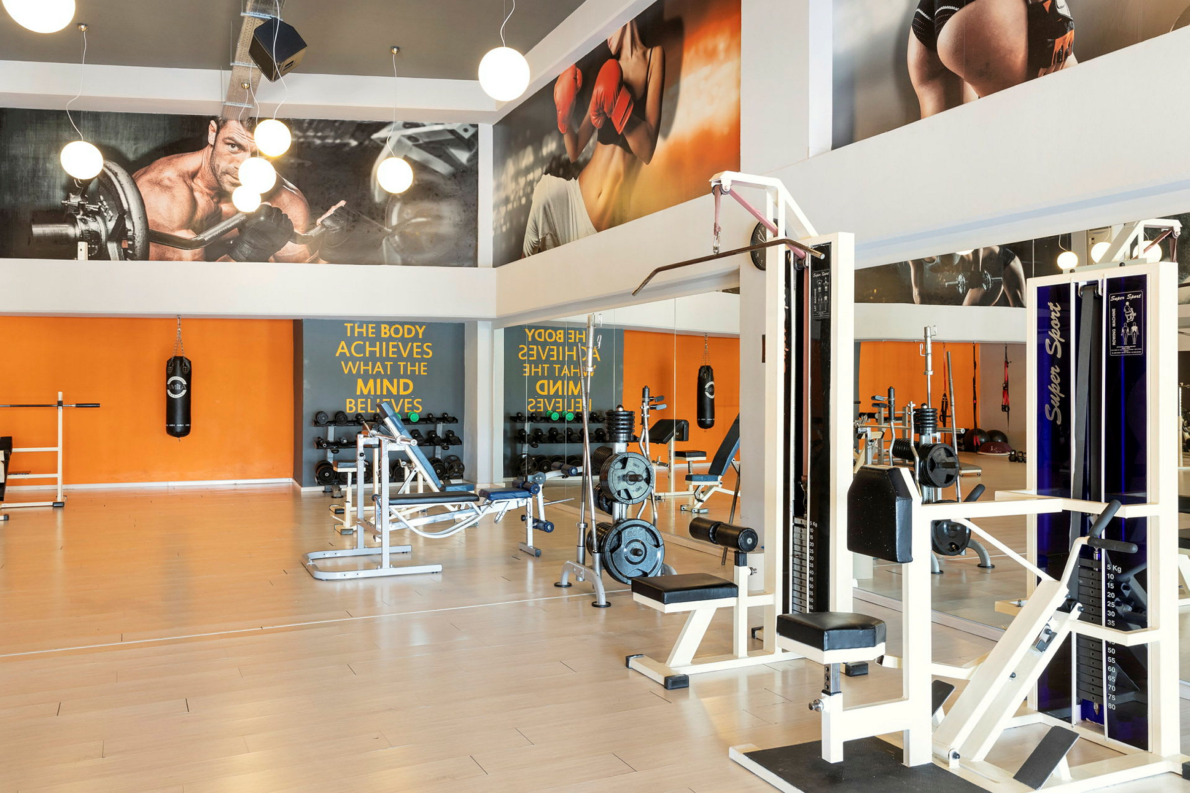 Et træningscenter med træningsmaskiner, fitnessudstyr og spejlvægge. (AI-genereret tekst)