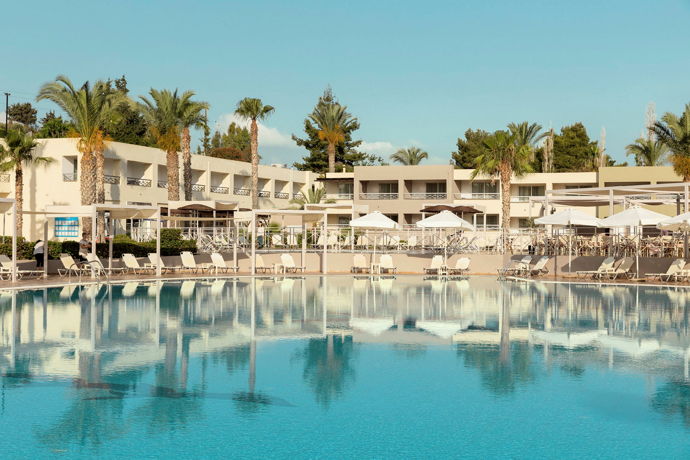 Et hotelområde med en stor swimmingpool og liggestole. (AI-genereret tekst)