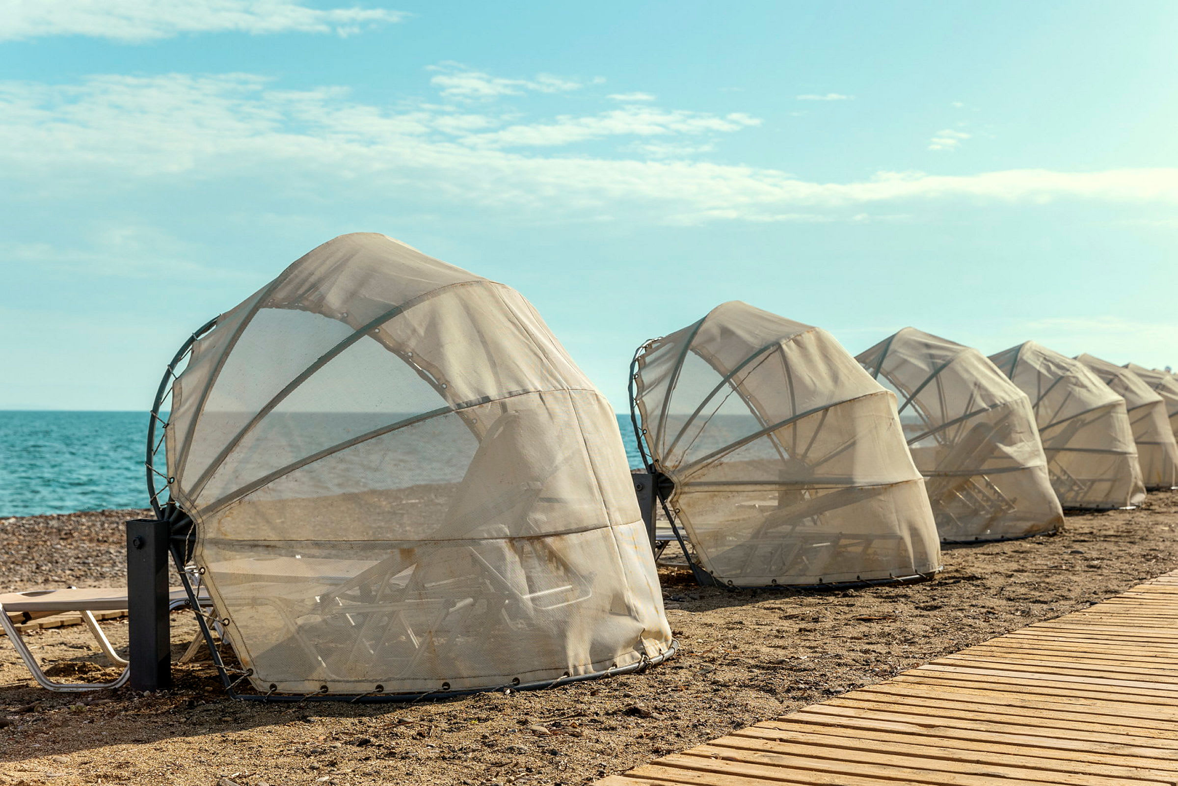 Beskyttede liggestole på stranden nær havet. (AI-genereret tekst)