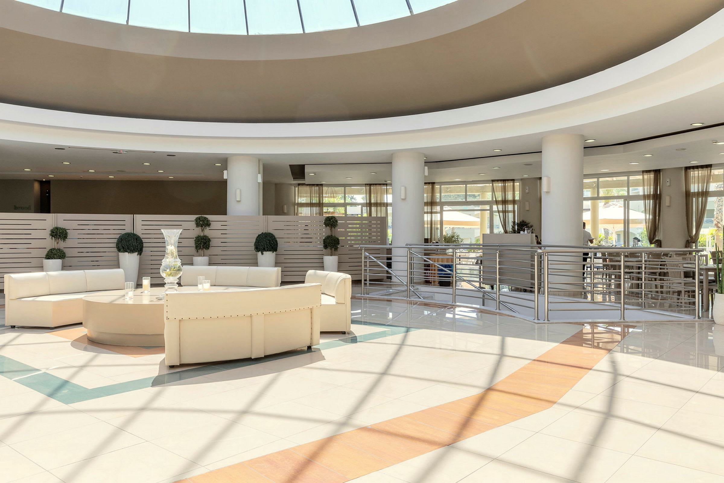 Billede af en moderne hotellobby med hvide møbler og store vinduer. (AI-genereret tekst)