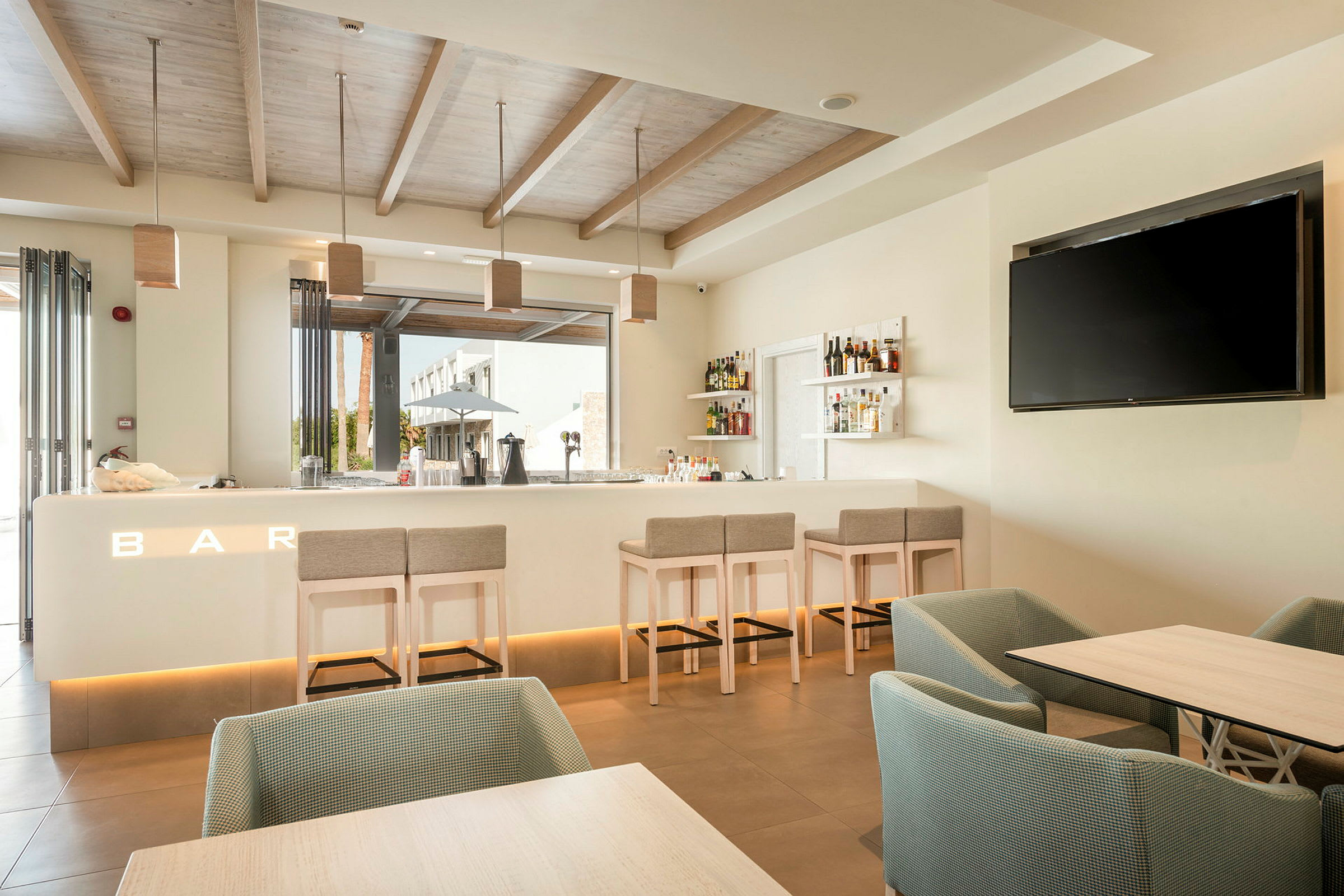 En moderne bar med stole, borde og et stort TV på væggen. (AI-genereret tekst)