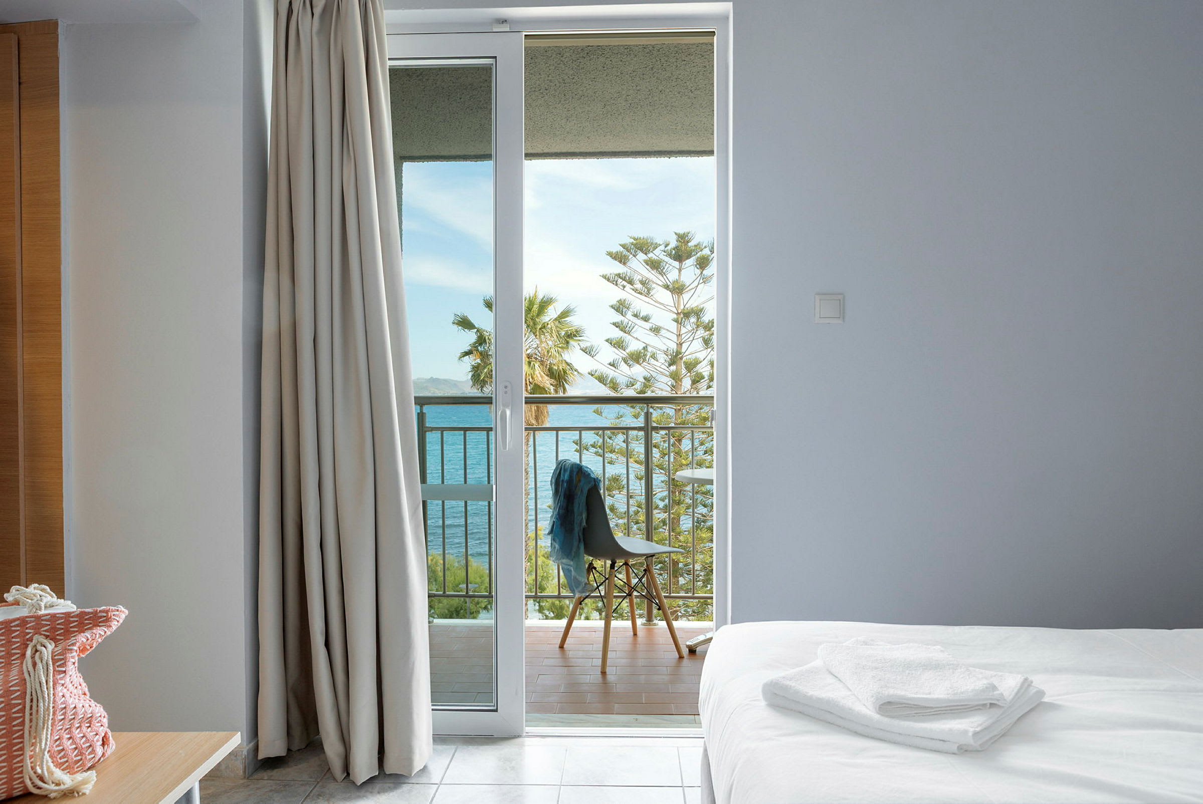 Udsigt fra værelse med balkon, havet og træer i baggrunden. (AI-genereret tekst)