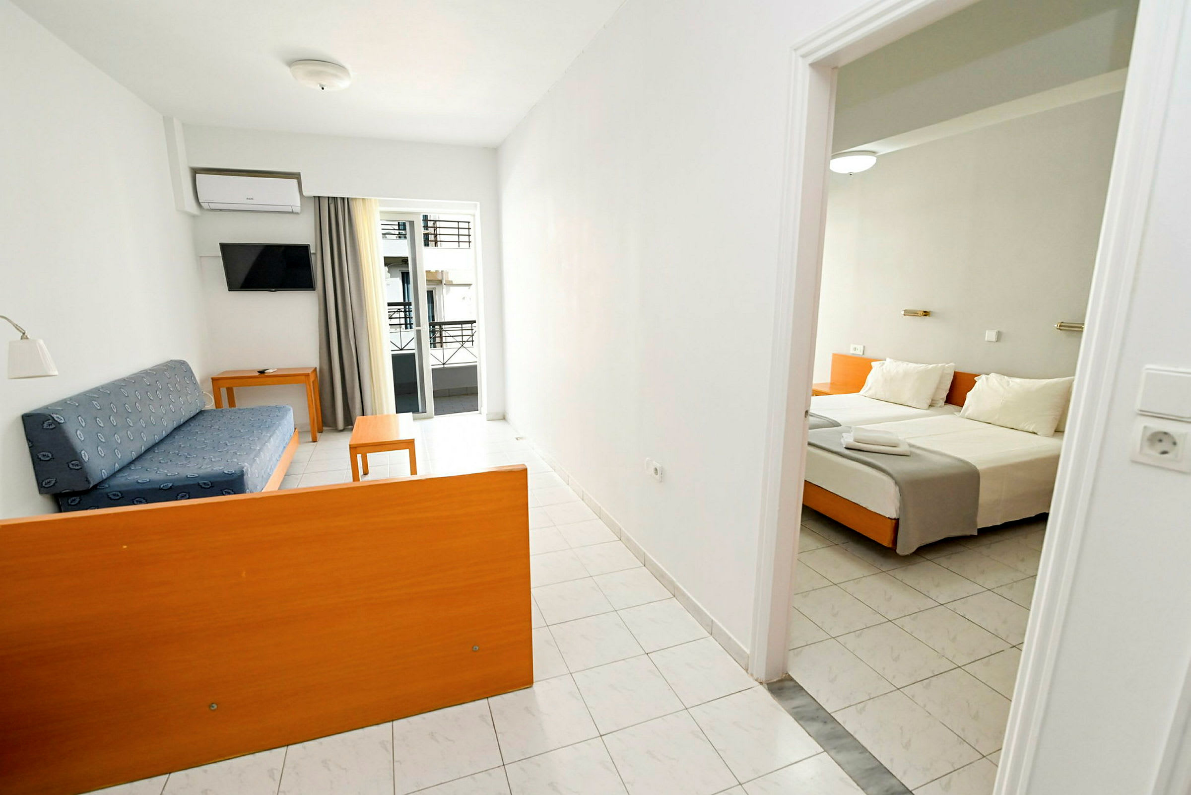 Et hotelværelse med et opholdsområde med en blå sofa og bord samt et soveområde med en dobbeltseng. (AI-genereret tekst)