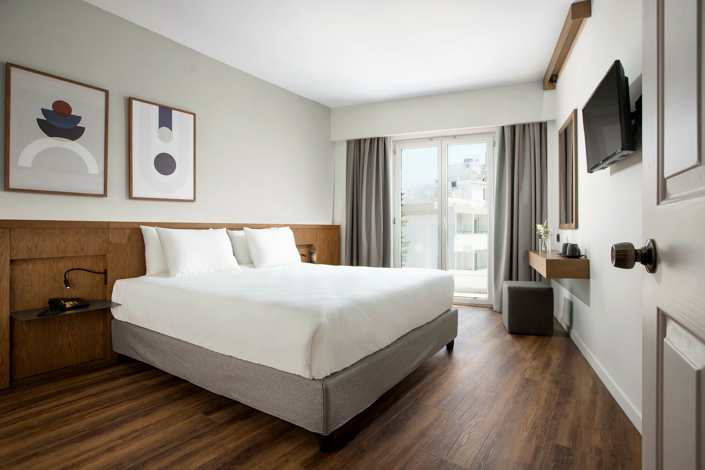 Moderne hotelværelse med dobbeltseng, kunst på væggen og altan med glasdør. (AI-genereret tekst)