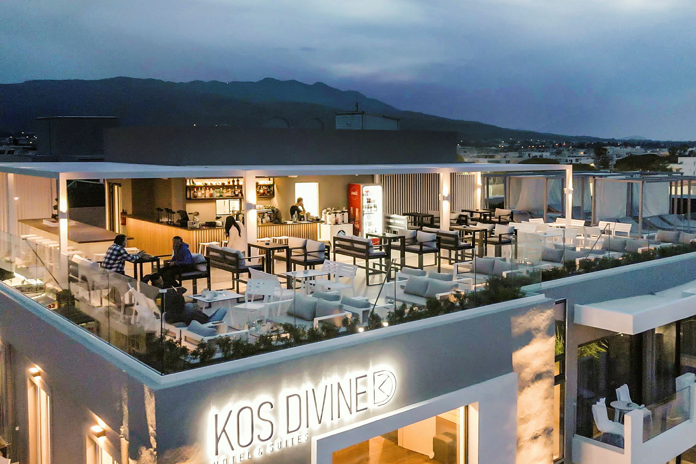 Billede af en oplyst tagrestaurant på et hotel med udendørsmøbler og udsigt over det omkringliggende landskab. (AI-genereret tekst)