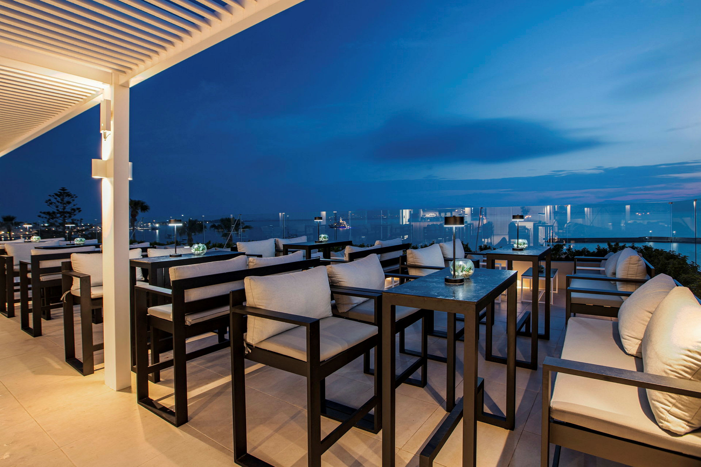 Elegant terrasse-lounge med siddepladser og udsigt over nattehimlen og havet. (AI-genereret tekst)
