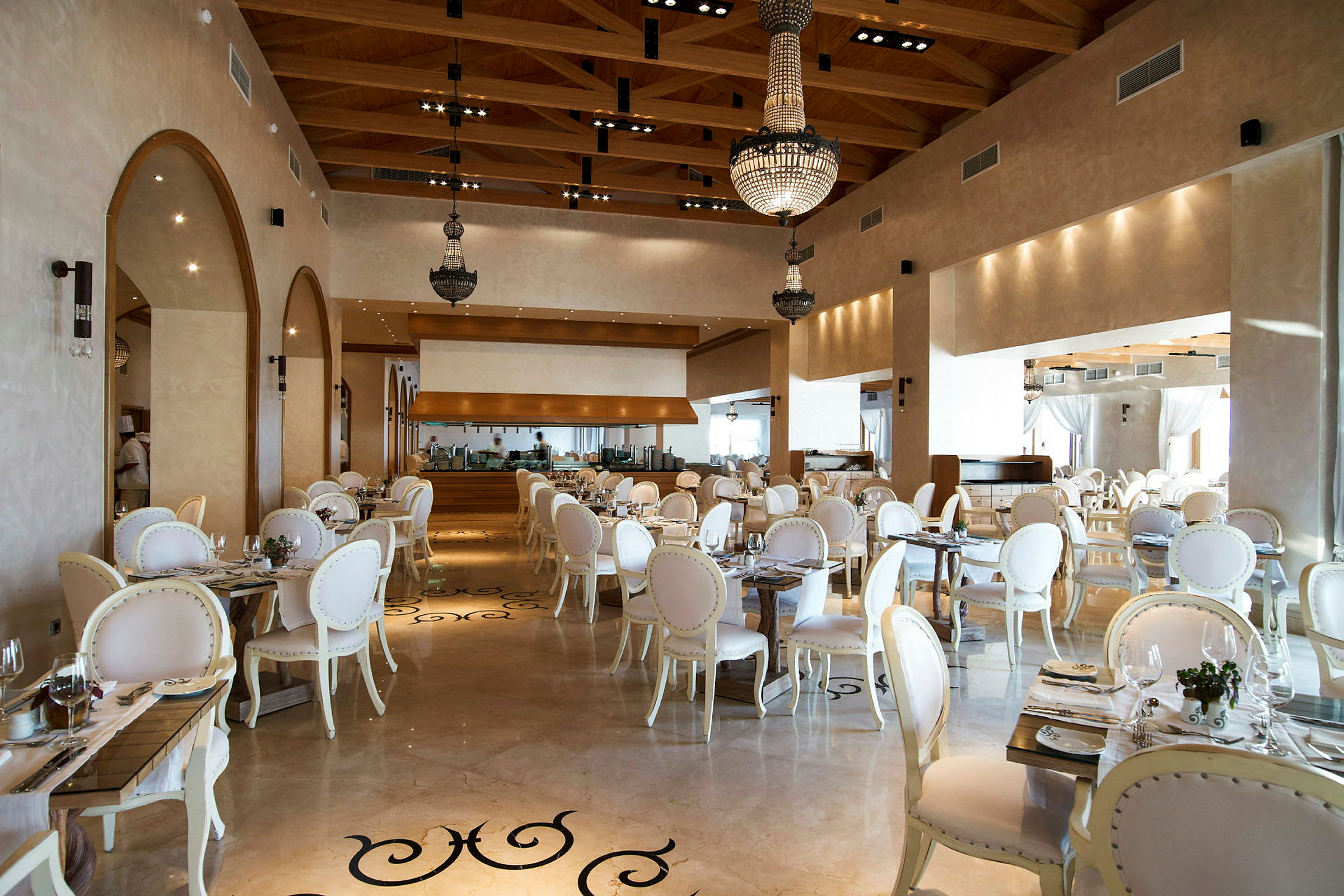En elegant restaurant med hvide stole og borde, dekoreret med lysekroner. (AI-genereret tekst)