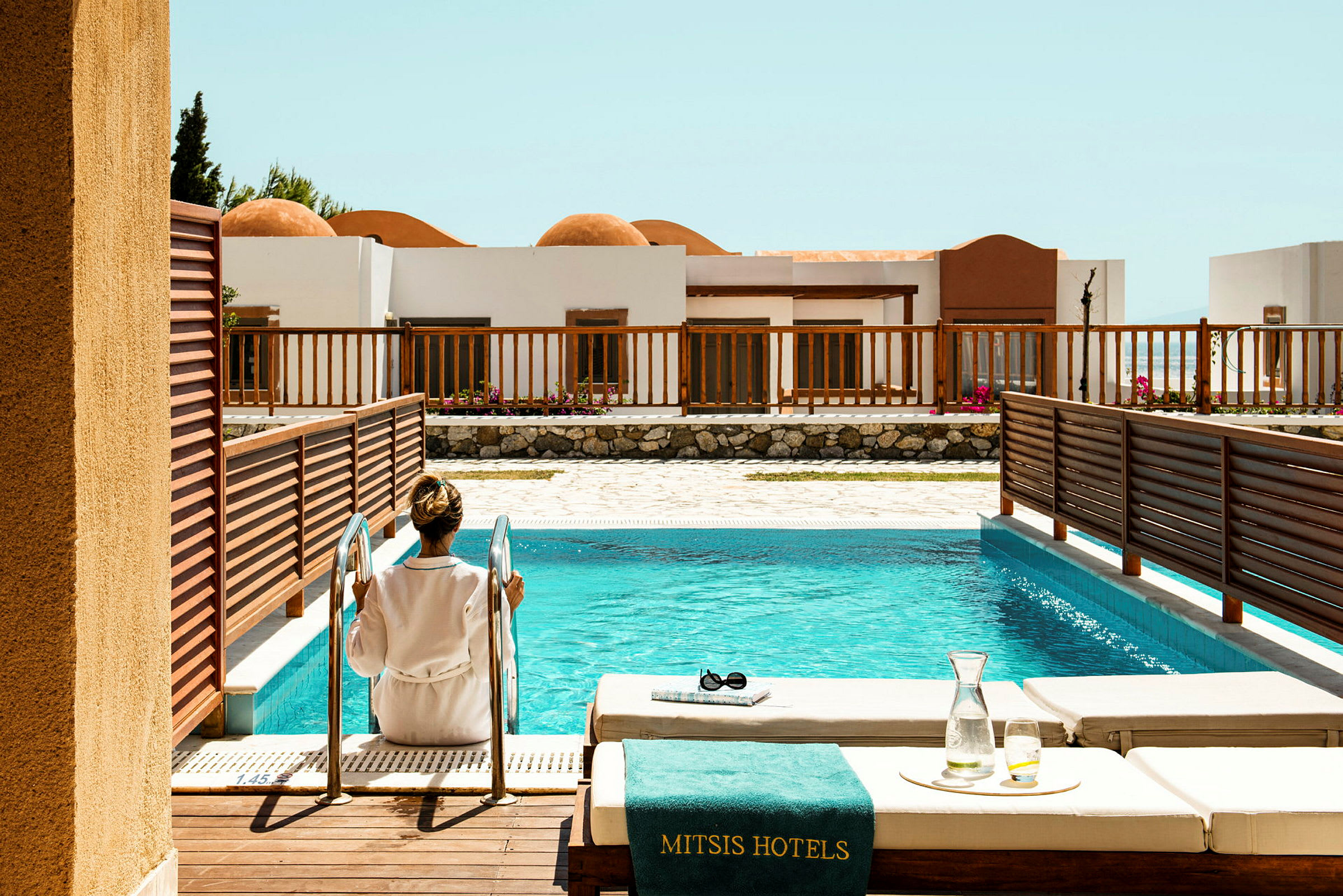En person sidder ved stigen til en hotelpool. (AI-genereret tekst)