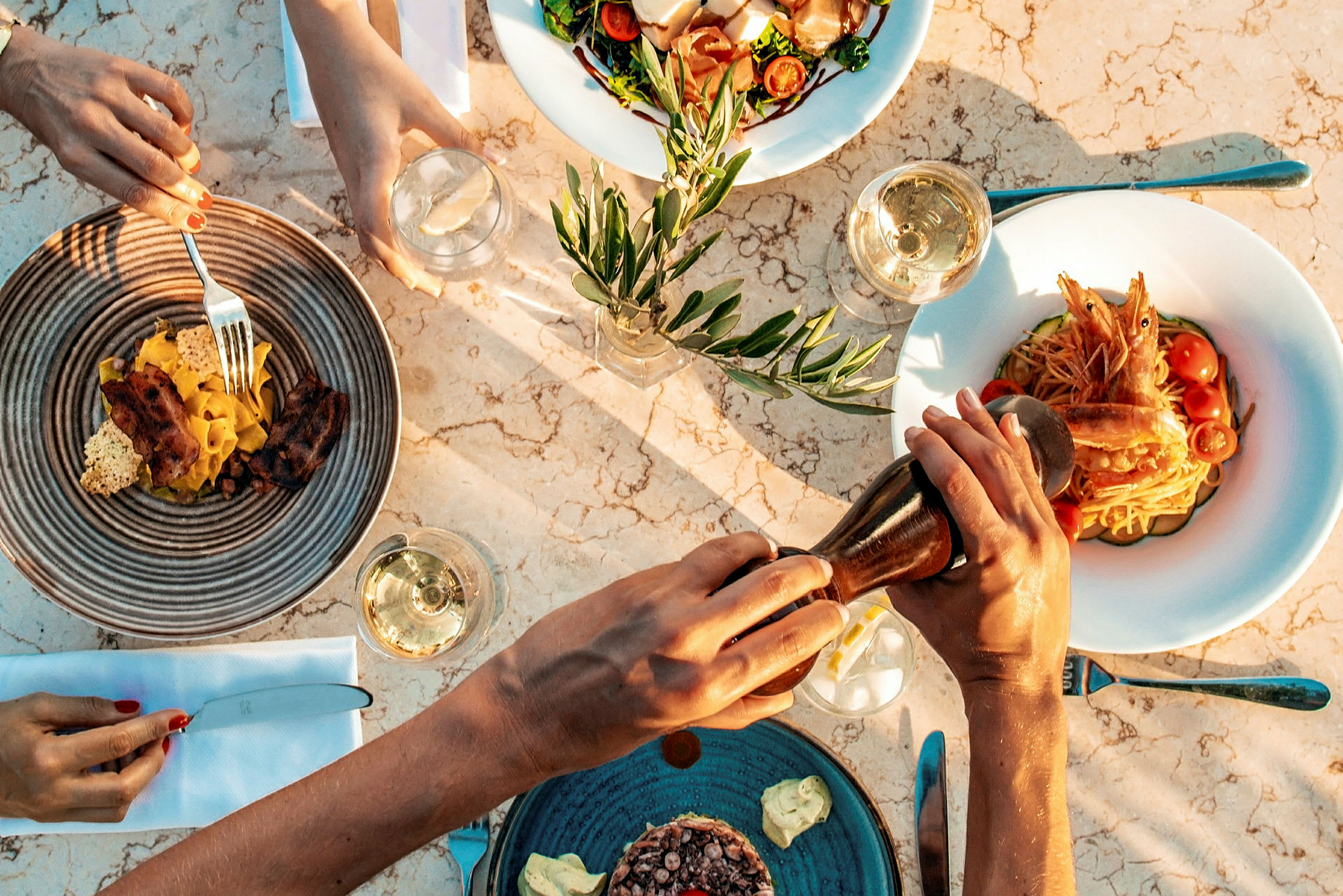 Fire tallerkener med forskellige retter og glas med drikke på en marmorbord. (AI-genereret tekst)