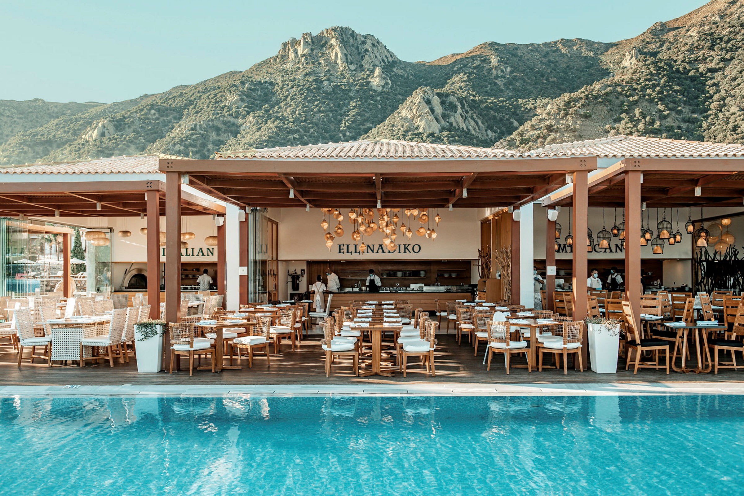 En restaurant ved en pool med udsigt over bjerge. (AI-genereret tekst)