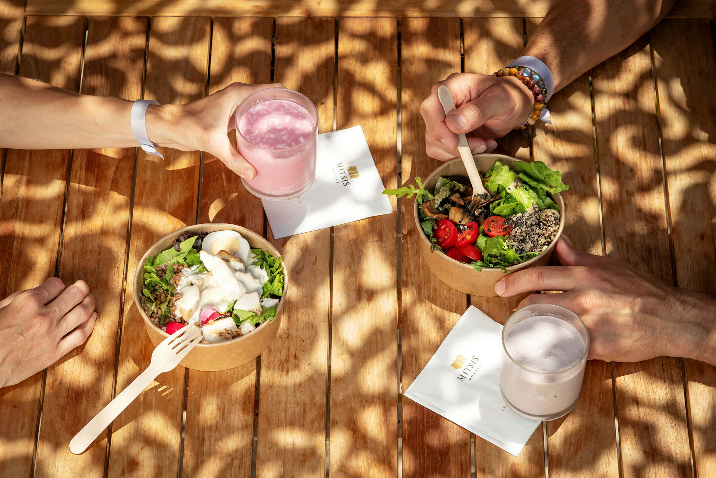 En hånd holder et glas rosa drik ved siden af to skåle med salat. (AI-genereret tekst)