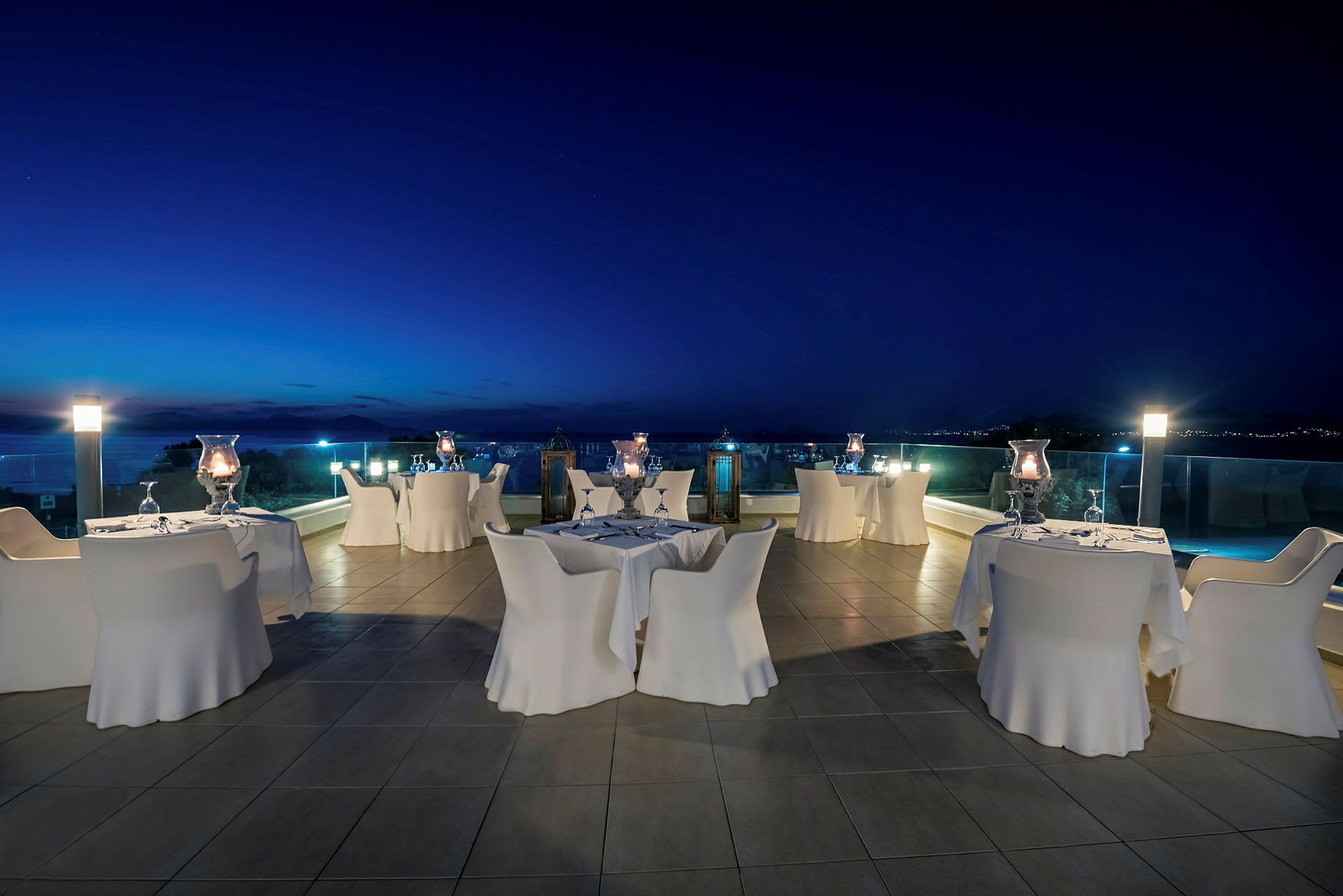 Smageborde på terrasse med udsigt over havet ved skumring. (AI-genereret tekst)