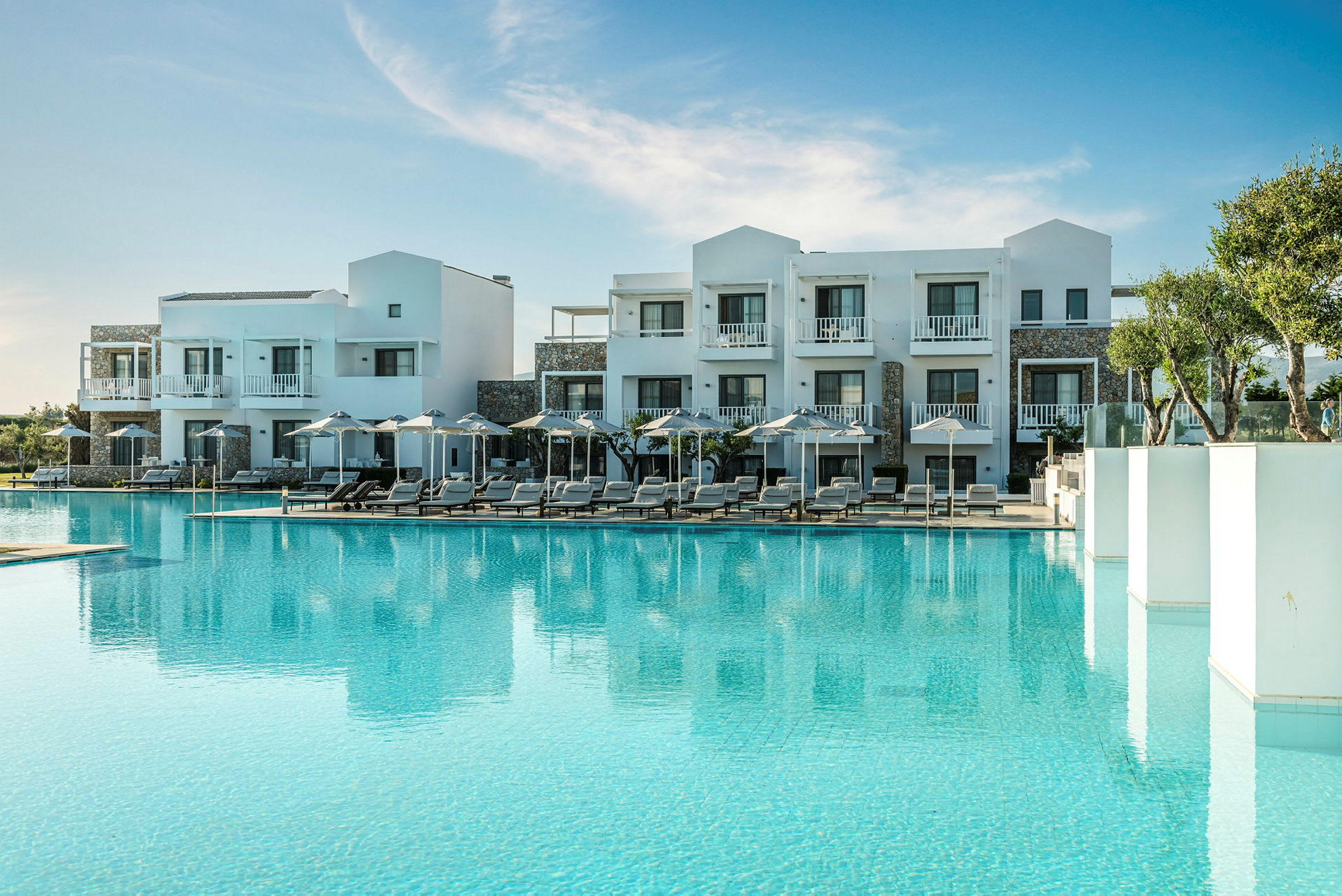 Hotelbygning med pool og solsenge i ømiljø. (AI-genereret tekst)