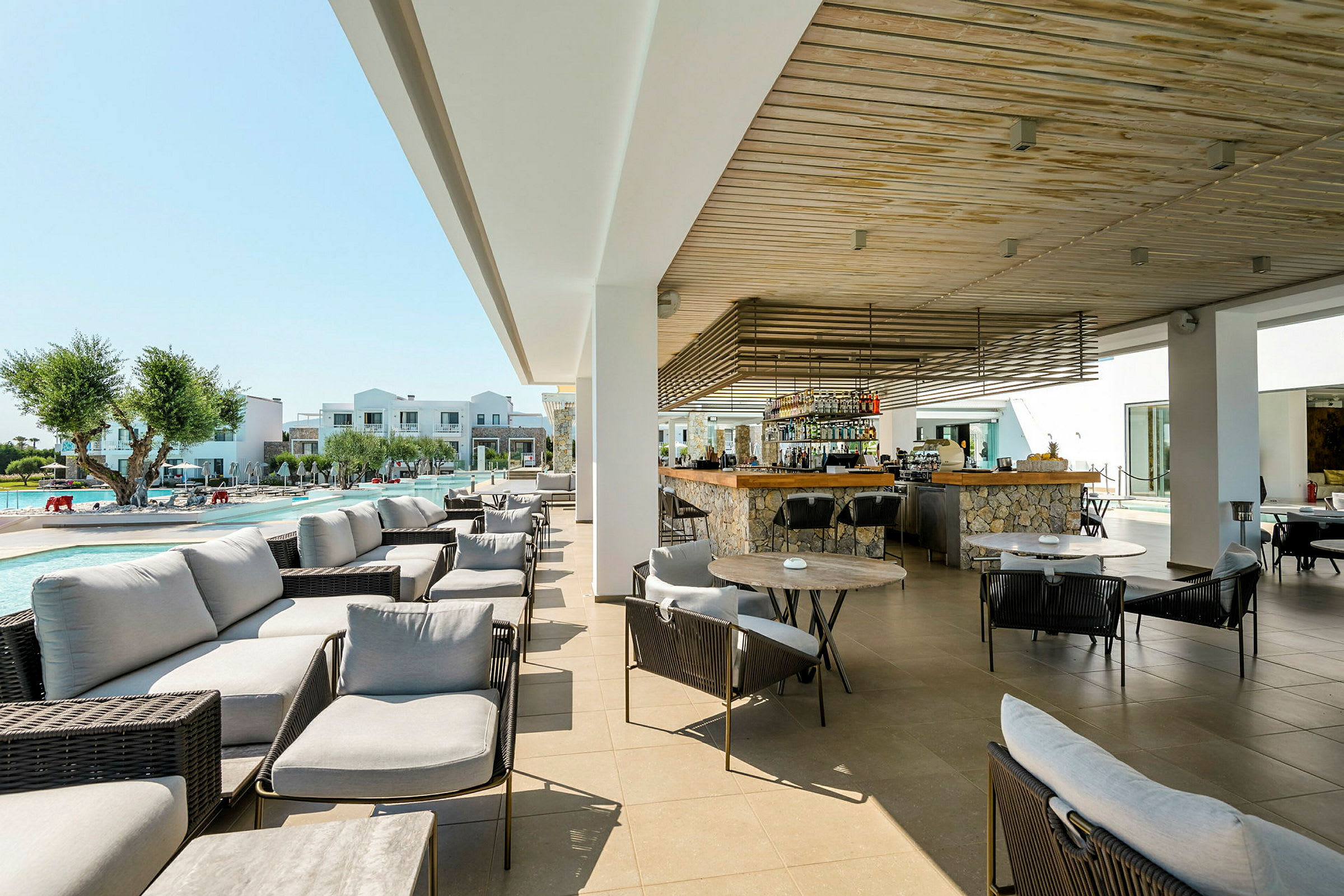 Udendørs loungeområde med borde og stole nær en pool og bar. (AI-genereret tekst)