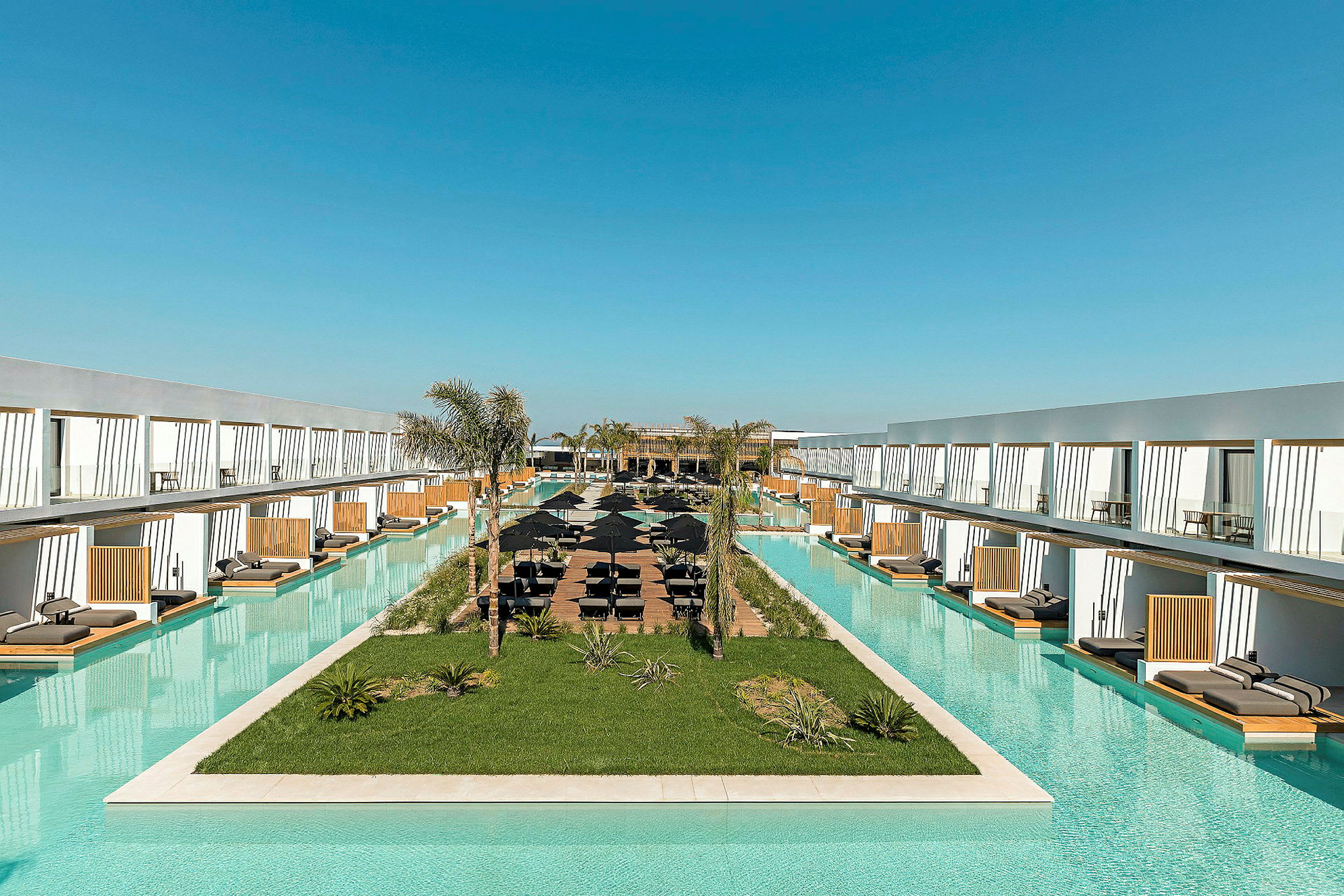 Lang pool omgivet af moderne hotelkompleks med liggestole. (AI-genereret tekst)