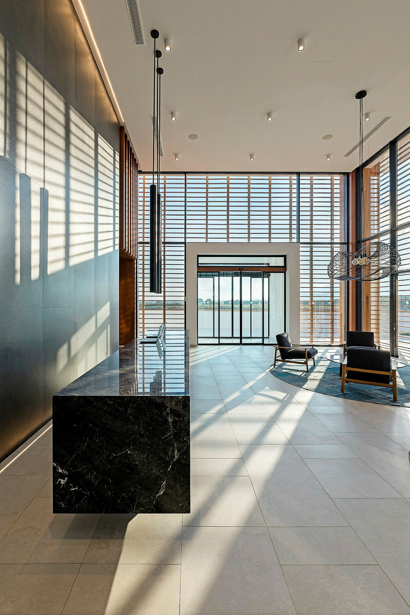 Moderne hotellobby med designermøbler og store vinduer, der lader dagslys strømme ind. (AI-genereret tekst)