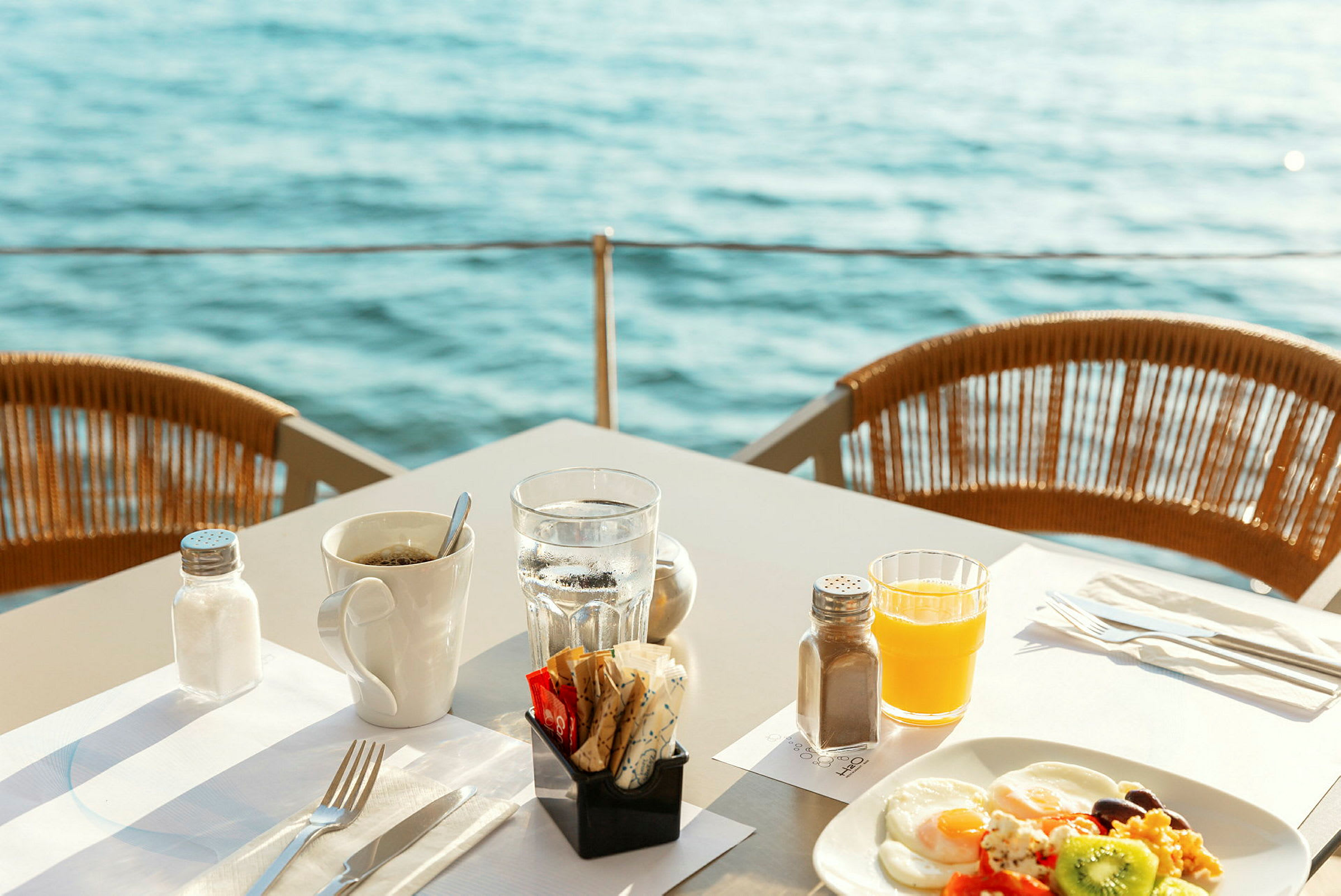 Morgenmad serveret ved bord med udsigt over vandet. (AI-genereret tekst)