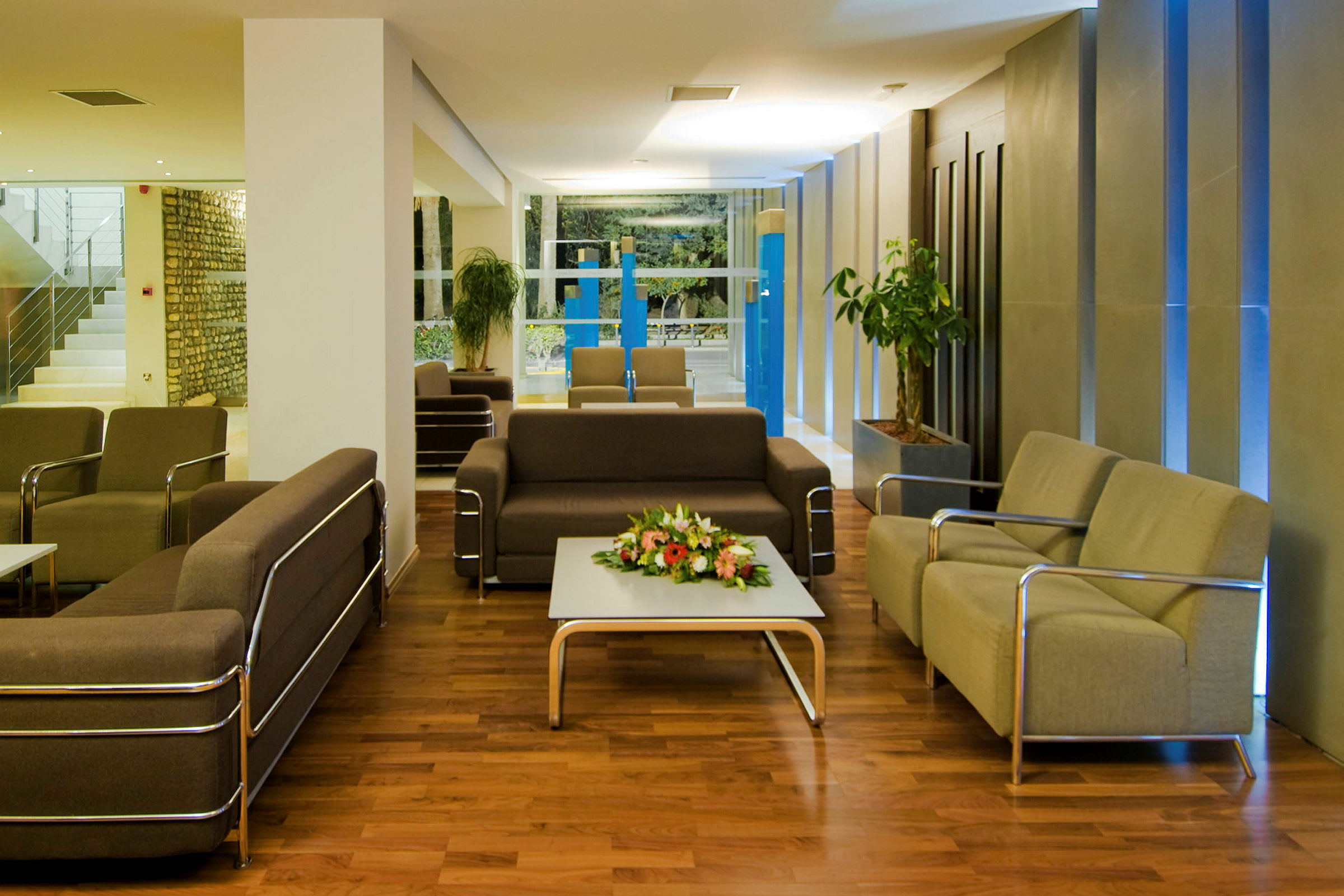 Et moderne loungeområde med sofaer, lænestole og et bord med blomster på. (AI-genereret tekst)