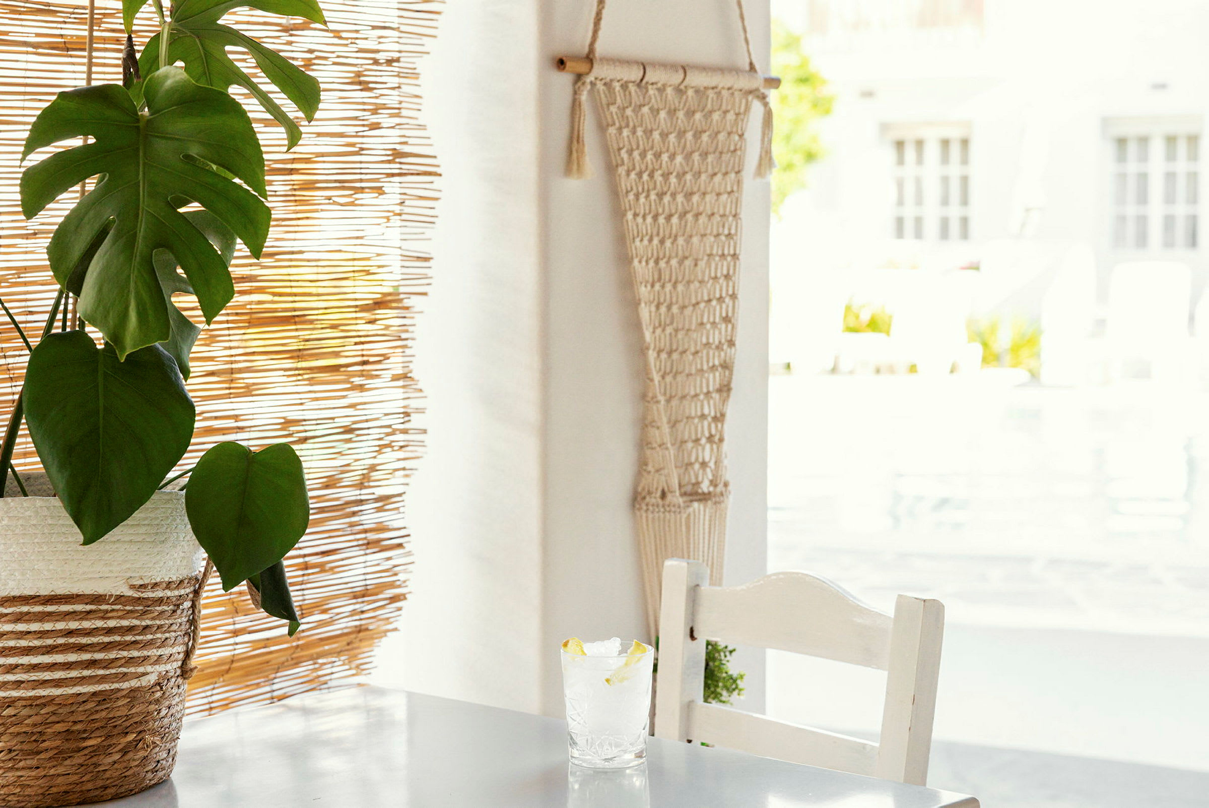 Bord med plante og glas med citron ved siden af bambuspersienne. (AI-genereret tekst)