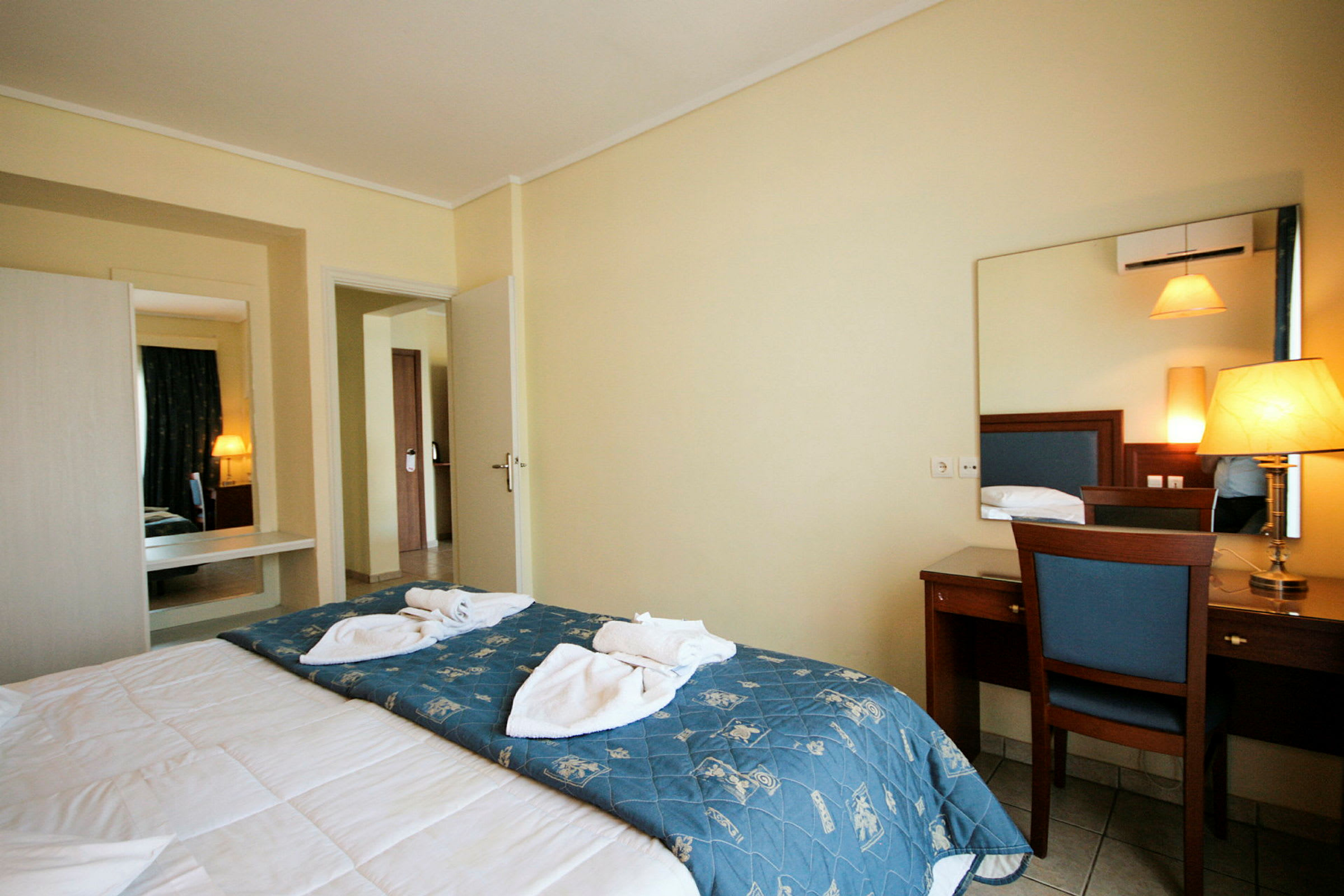 Interiør af et hotelværelse med en seng, spejl og skrivebord. (AI-genereret tekst)