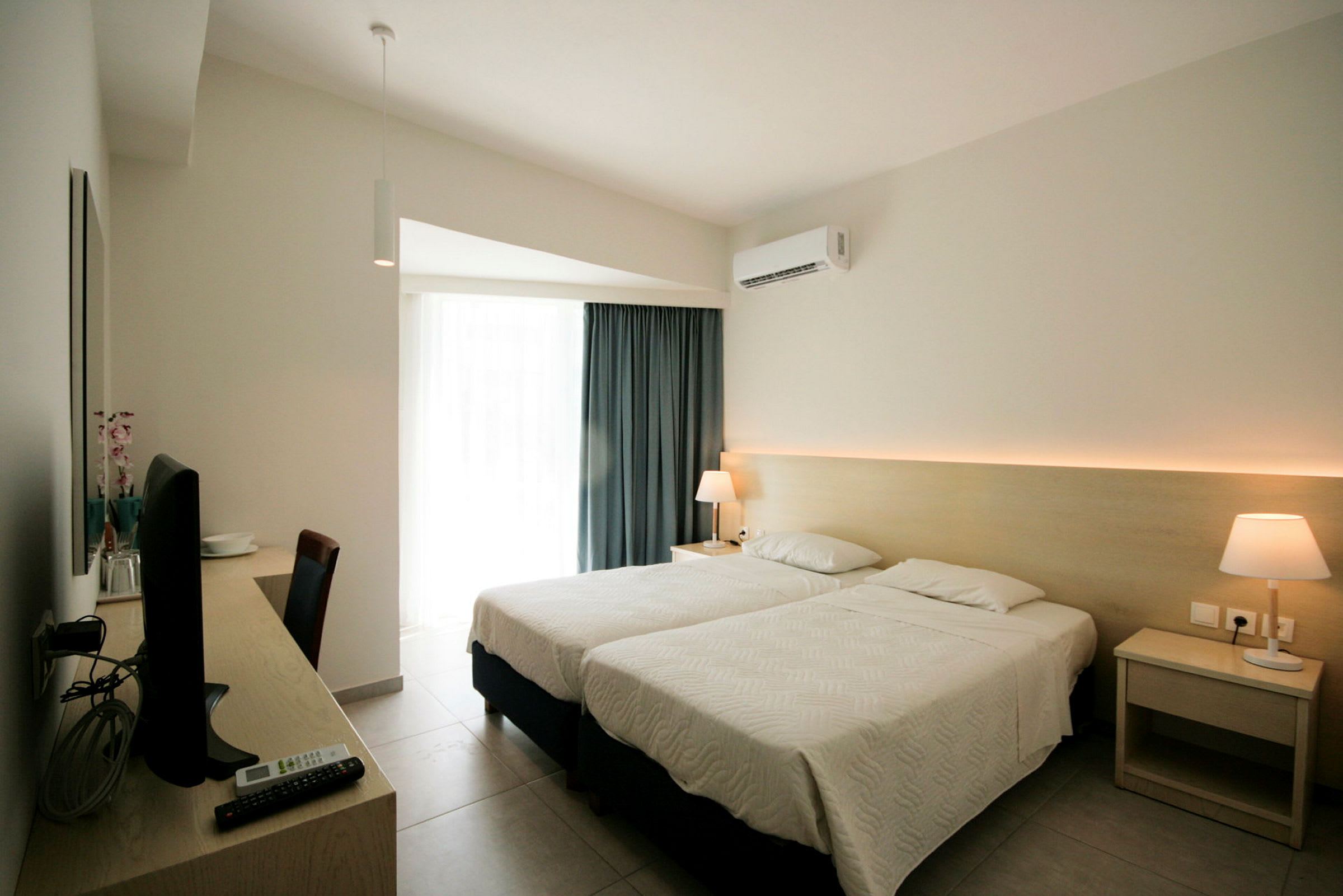 Hotelværelse med to enkeltsenge, skrivebord med tv og lampe på natbordet. (AI-genereret tekst)