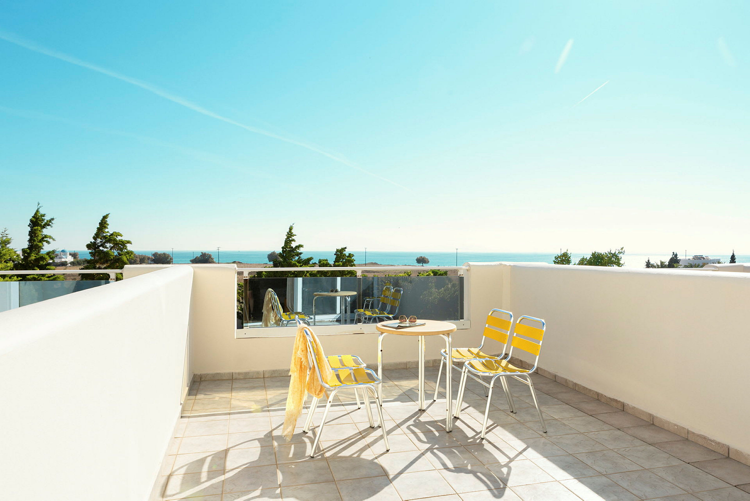 En terrasse med bord og stole, udsigt over havet og grønt. (AI-genereret tekst)