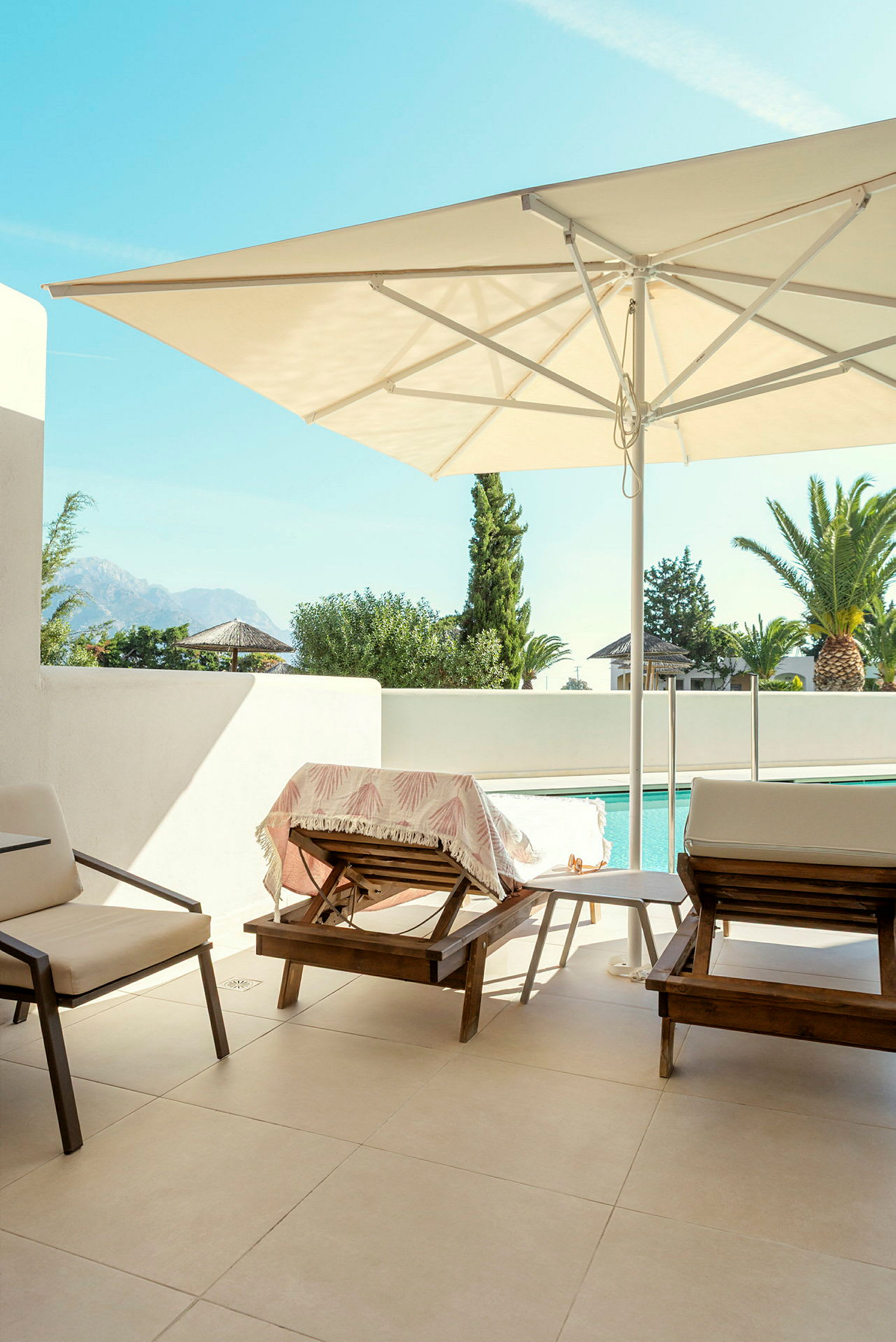 Billede af en terrasse med liggestole, parasol og swimmingpool i baggrunden. (AI-genereret tekst)