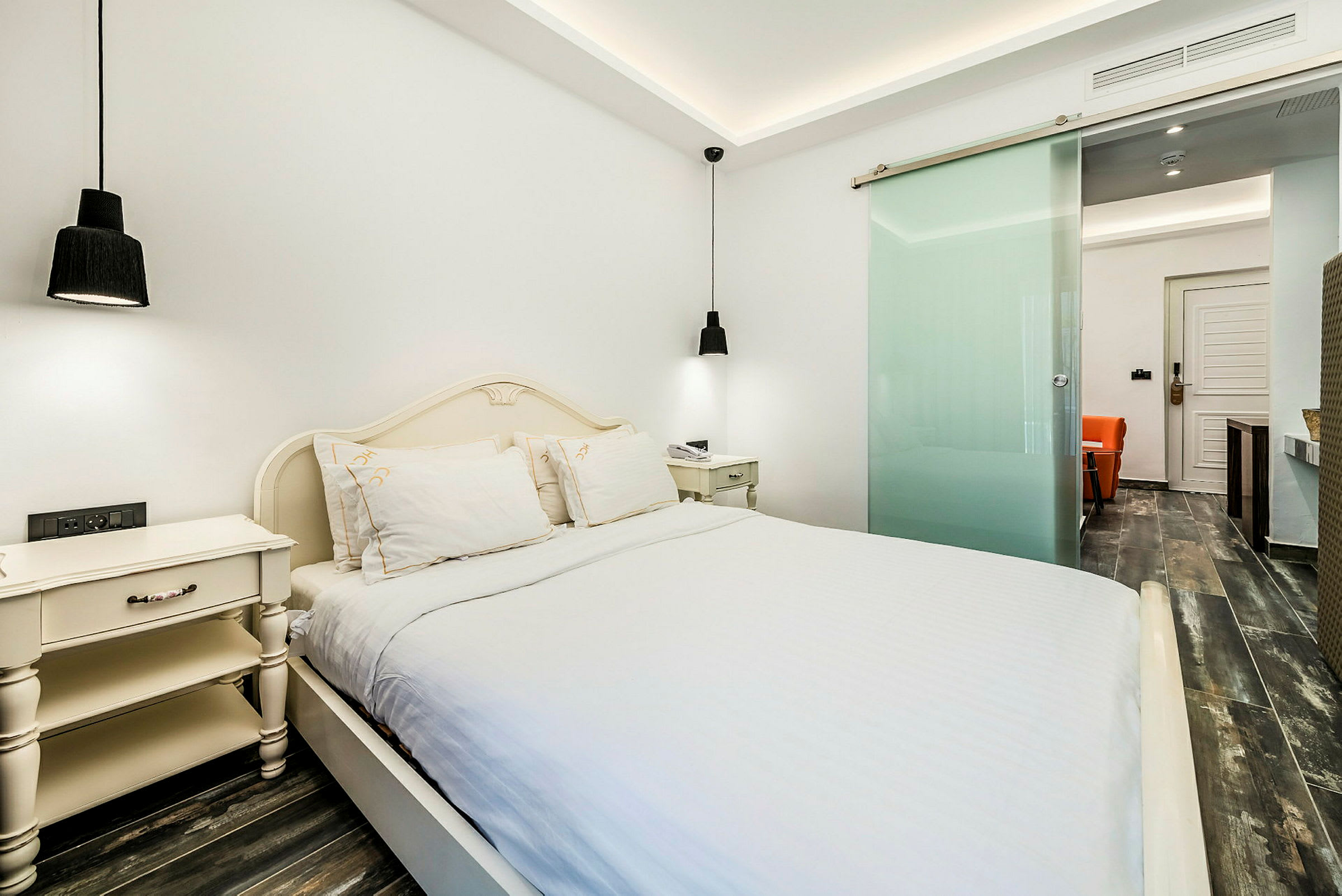 Et hotelværelse med en dobbeltseng, natborde og moderne designdetaljer. (AI-genereret tekst)