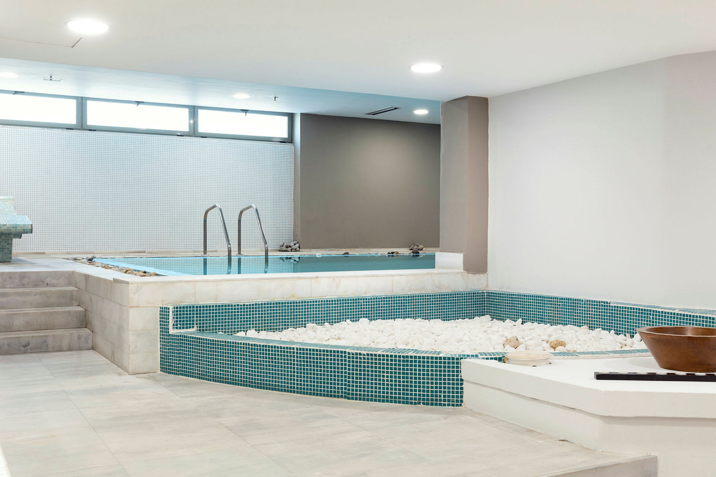 Et indendørs spa med en pool og dekorative hvide sten. (AI-genereret tekst)