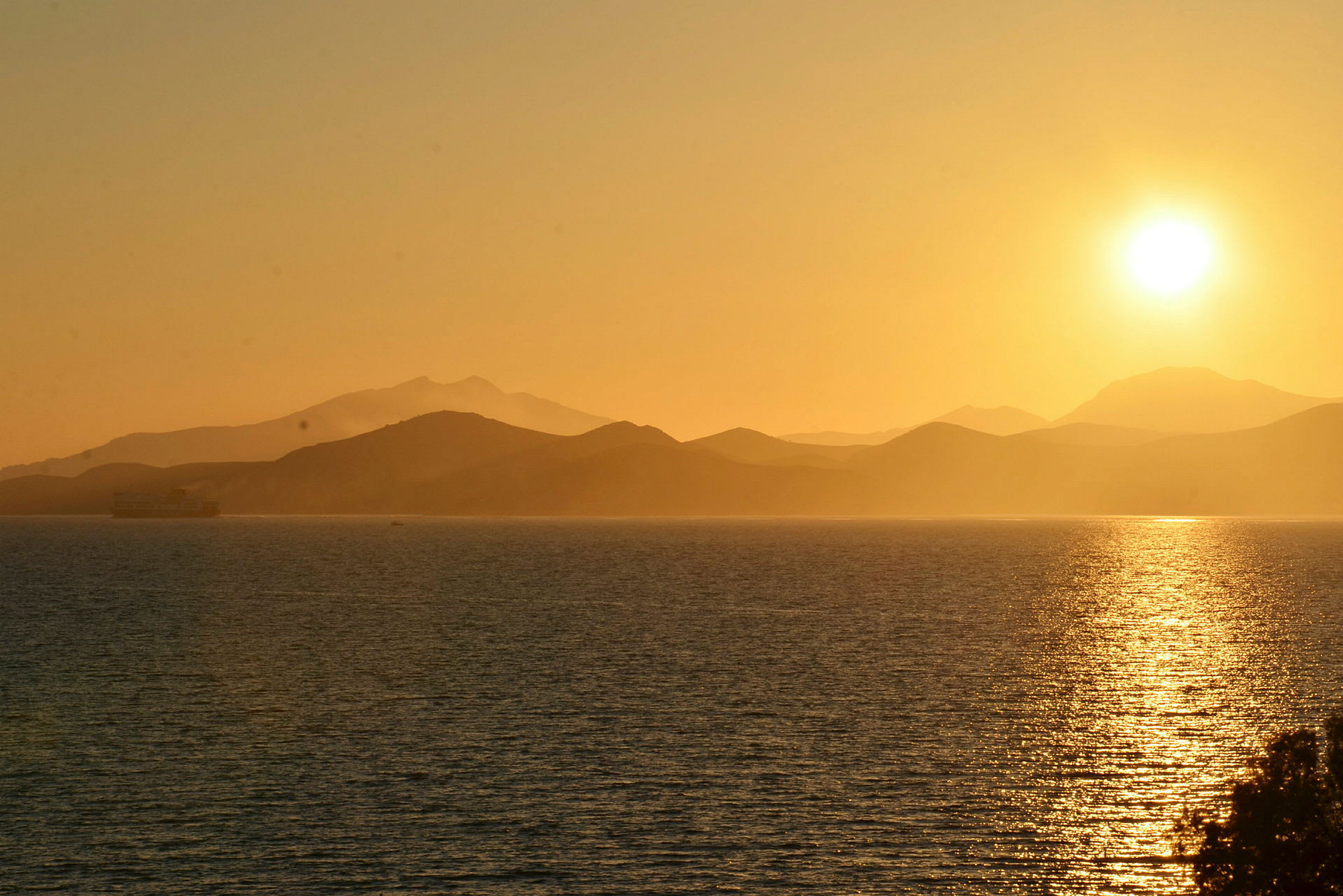 Solnedgang over en havudsigt med bjerge i baggrunden. (AI-genereret tekst)