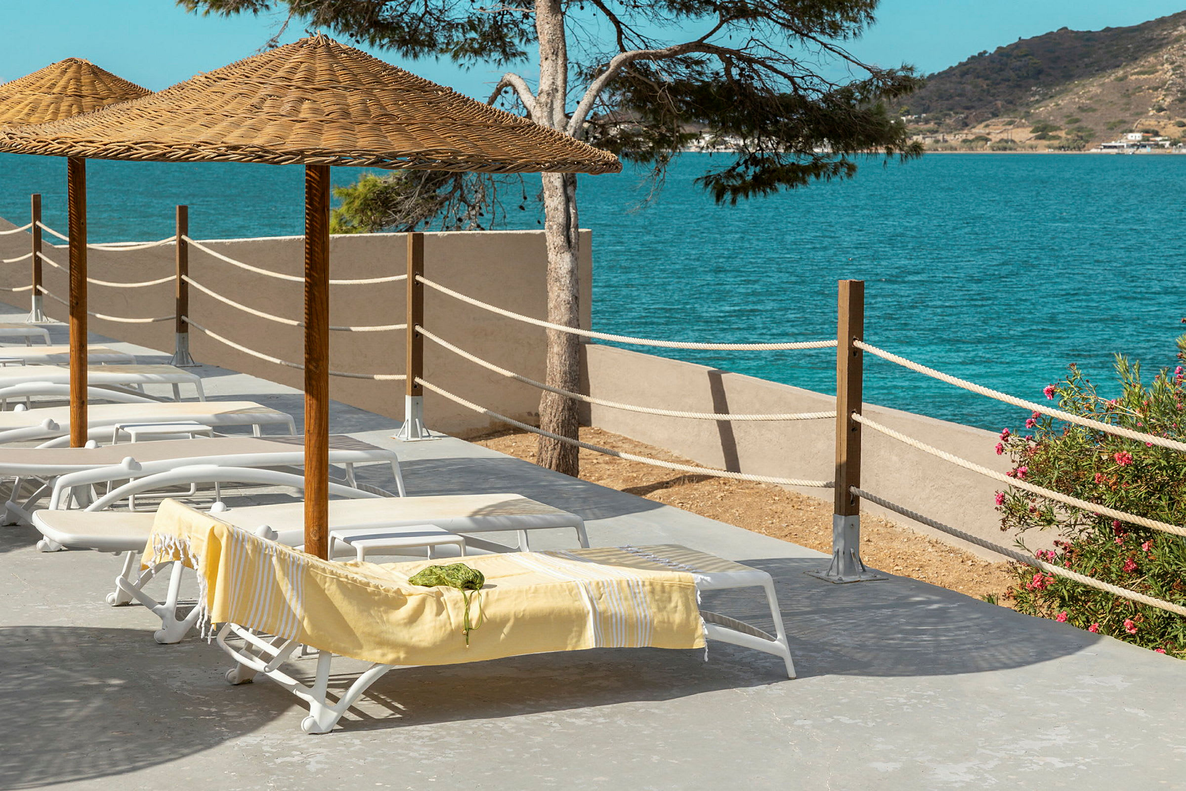 Liggestole under parasoller på en terrasse ved havet. (AI-genereret tekst)