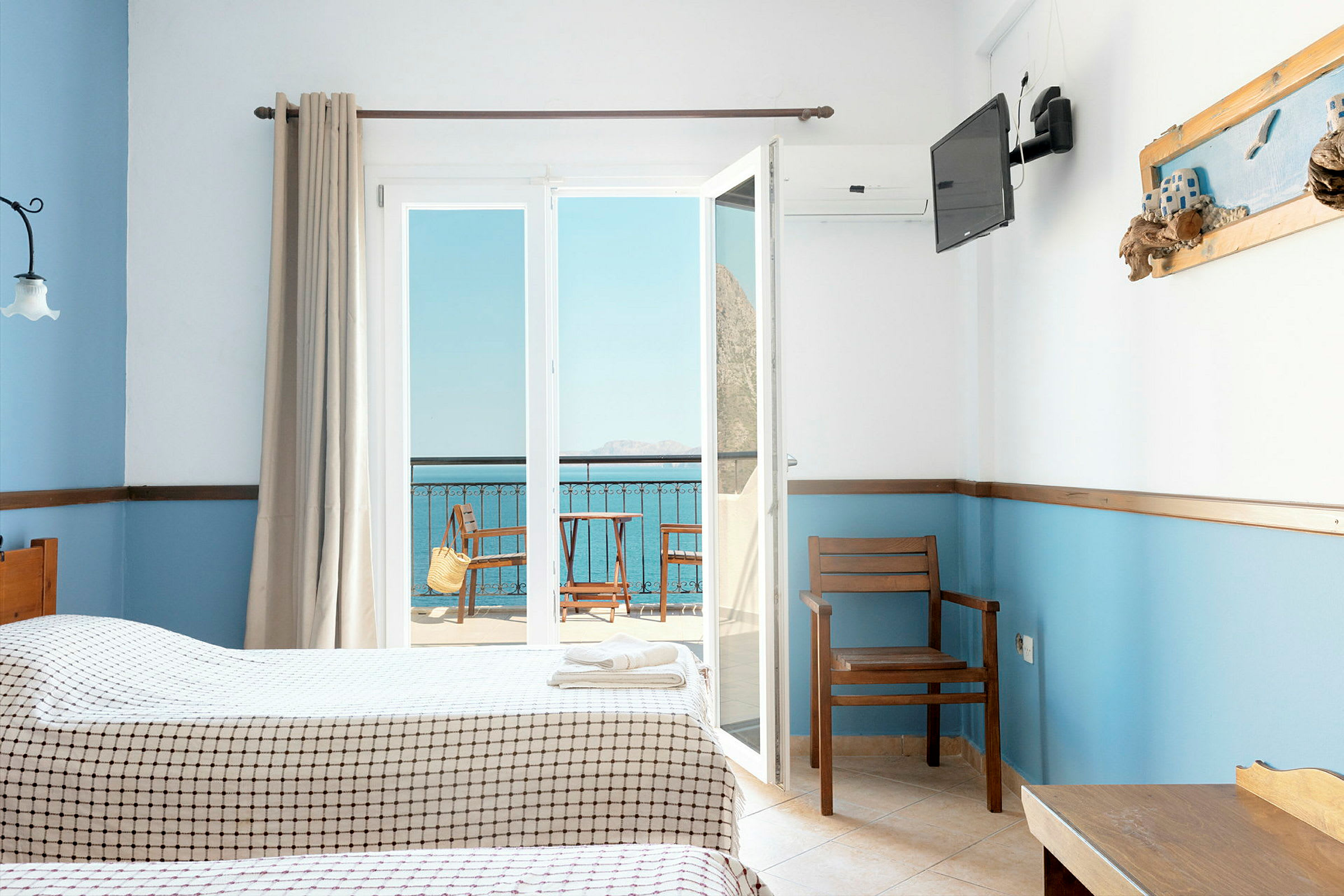 Hotelværelse med to senge, udsigt til en balkon og havet. (AI-genereret tekst)