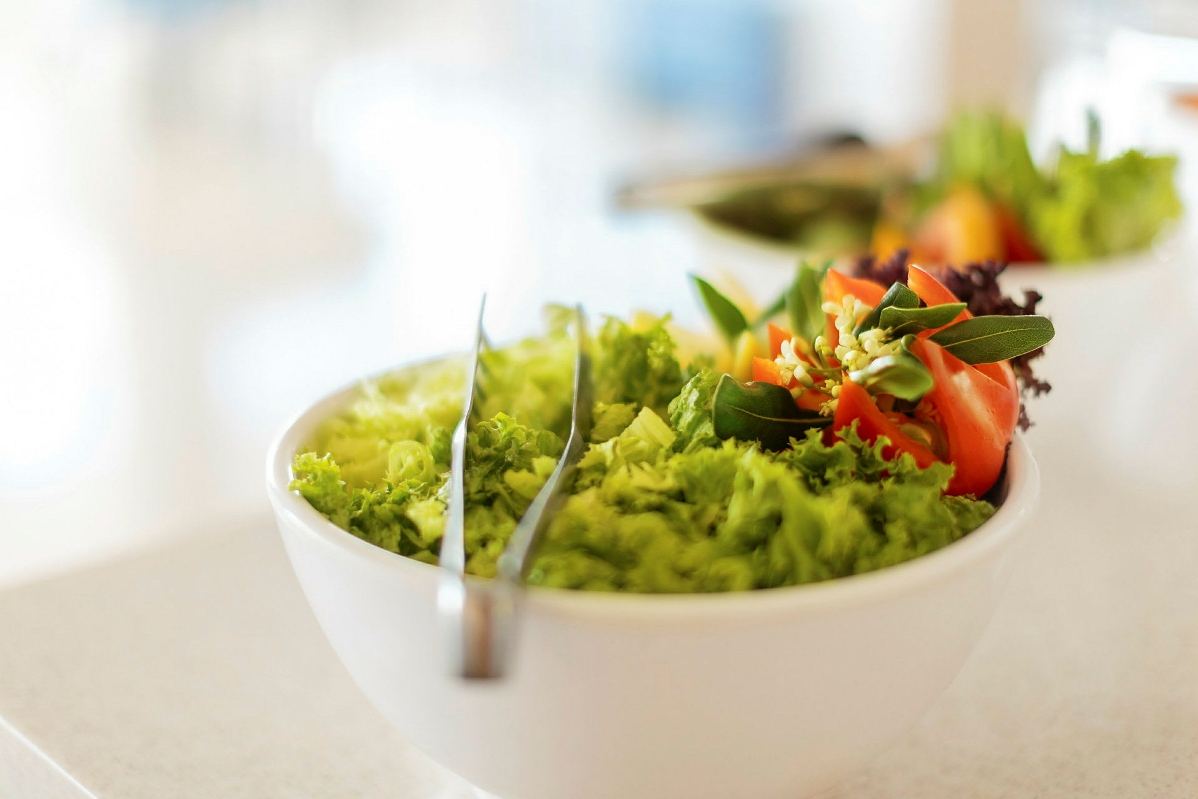 En salat i en hvid skål med dekorative grøntsager. (AI-genereret tekst)