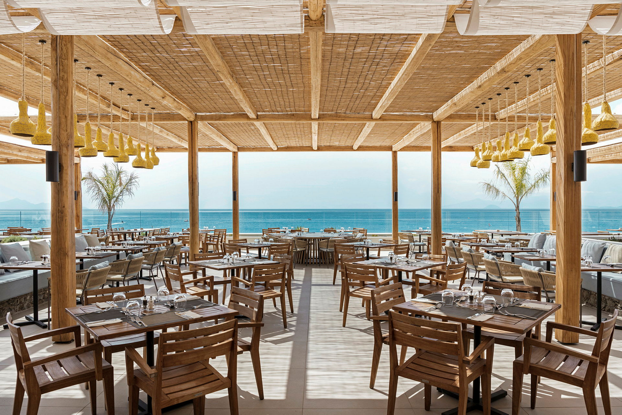 Restaurant med træmøbler og udsigt til havet. (AI-genereret tekst)