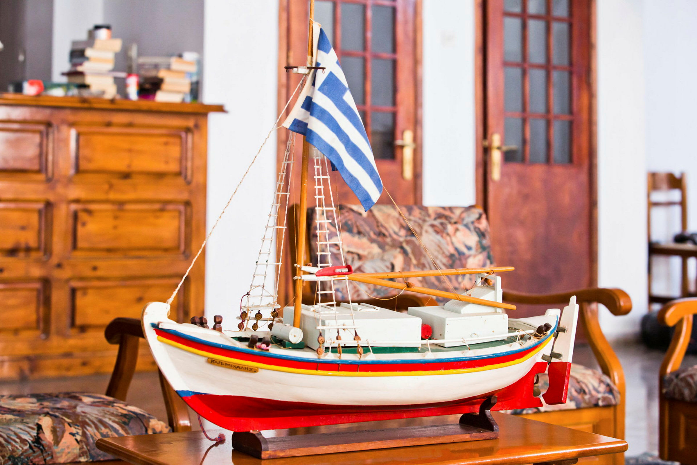 Model af en båd med græsk flag på et bord. (AI-genereret tekst)