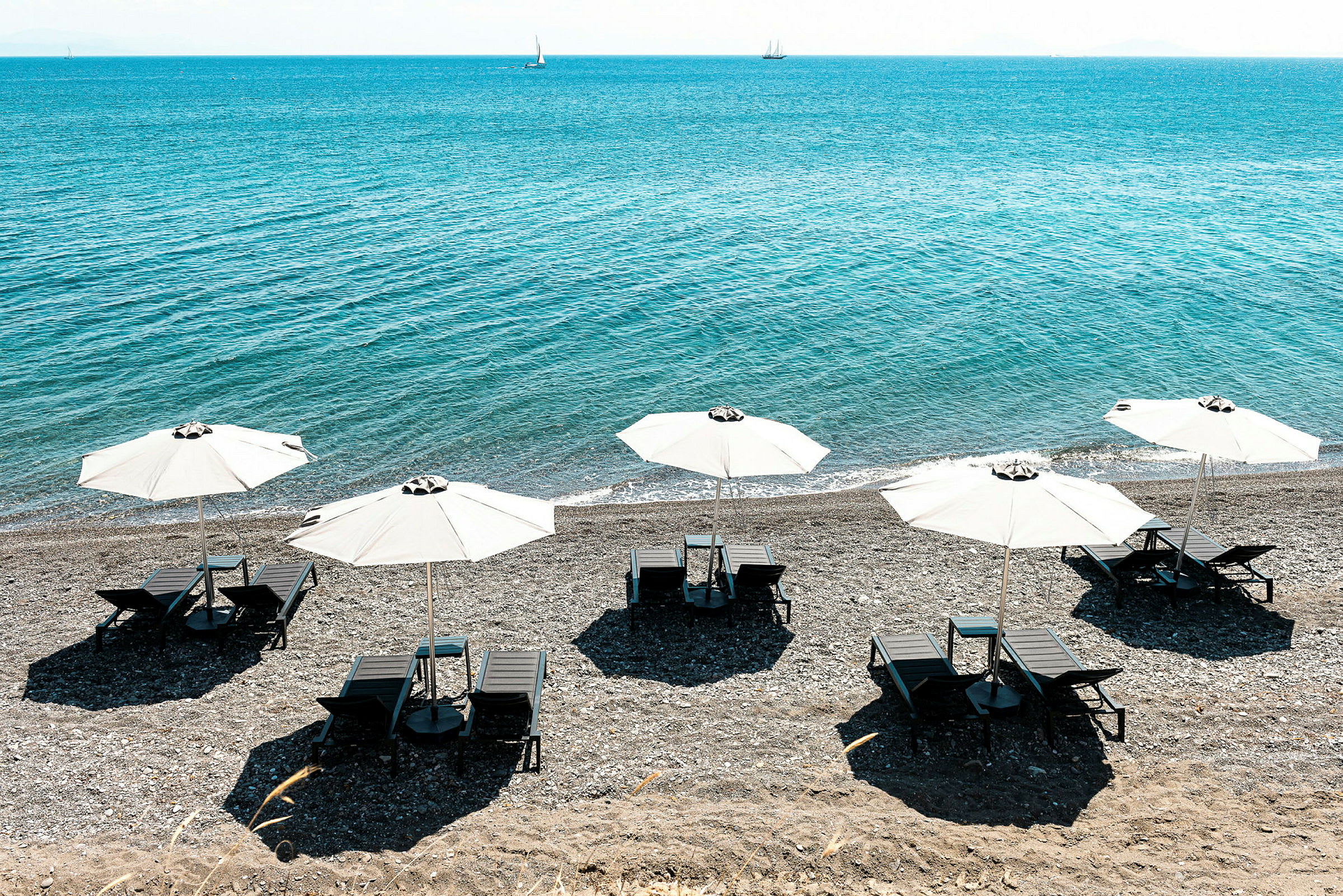 Strand med solsenge under hvide parasoller ved havet. (AI-genereret tekst)