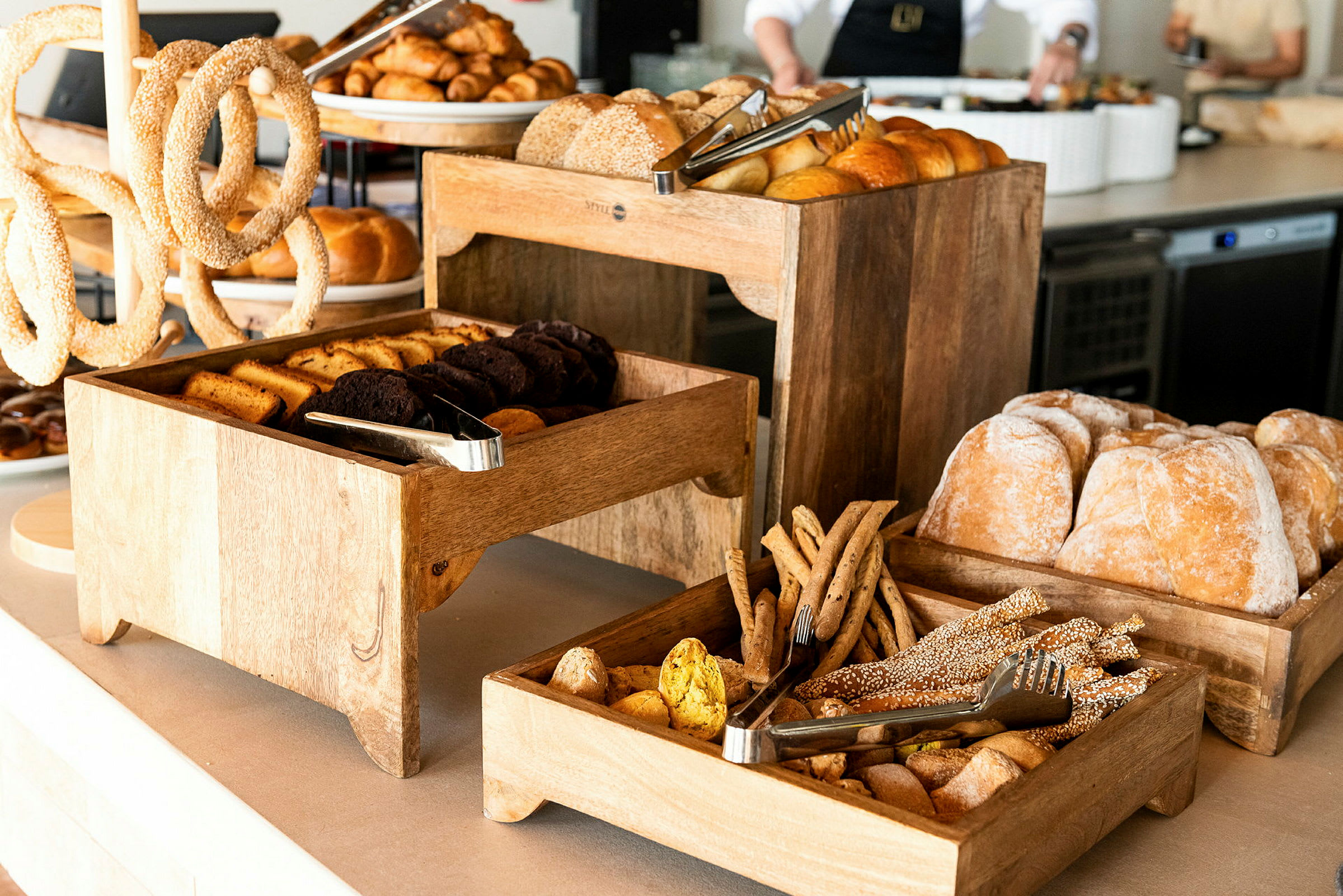 En buffet med forskellige slags brød og bagværk præsenteret i træbakker. (AI-genereret tekst)