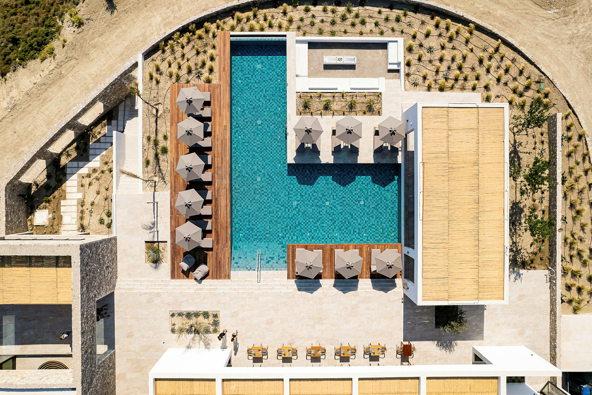 Luftfoto af en pool omgivet af liggestole og parasoller. (AI-genereret tekst)