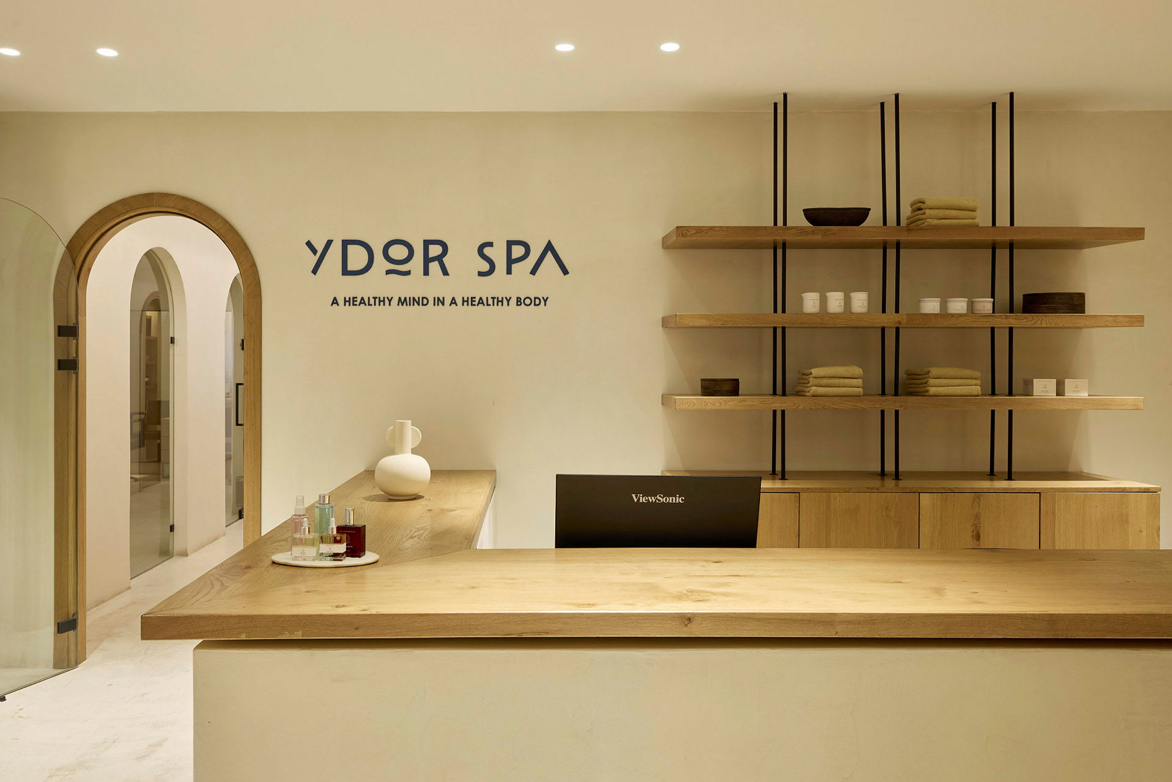 En receptionsskranke i en spa med produkter og håndklæder på hylder bagved. (AI-genereret tekst)