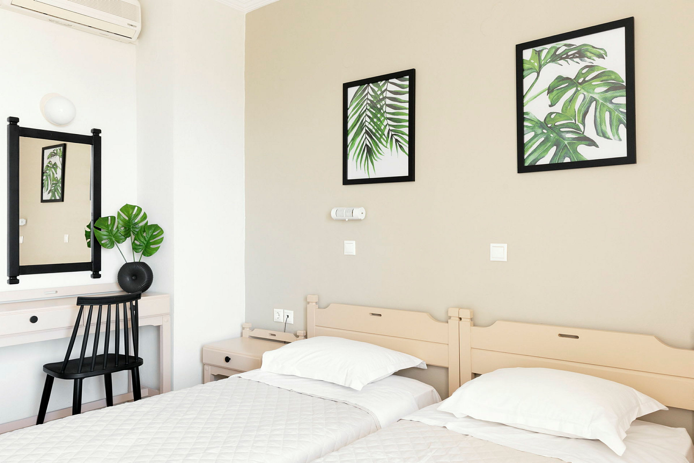 Hotelværelse med to enkeltsenge, et skrivebord og vægdekorationer med botaniske motiver. (AI-genereret tekst)