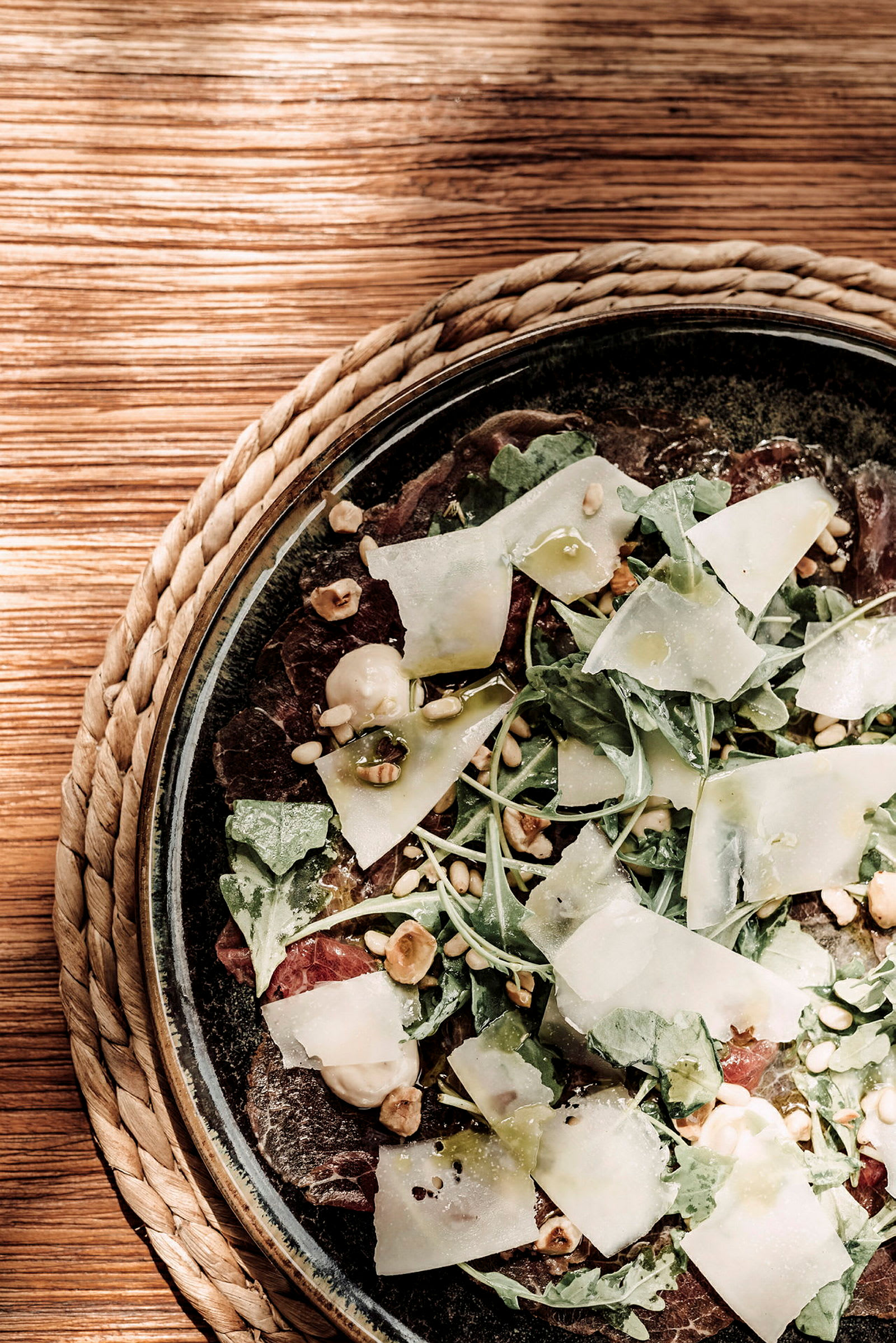 Nærbillede af en salat med rucola, tynde osteskiver, nødder og balsamico-dressing. (AI-genereret tekst)